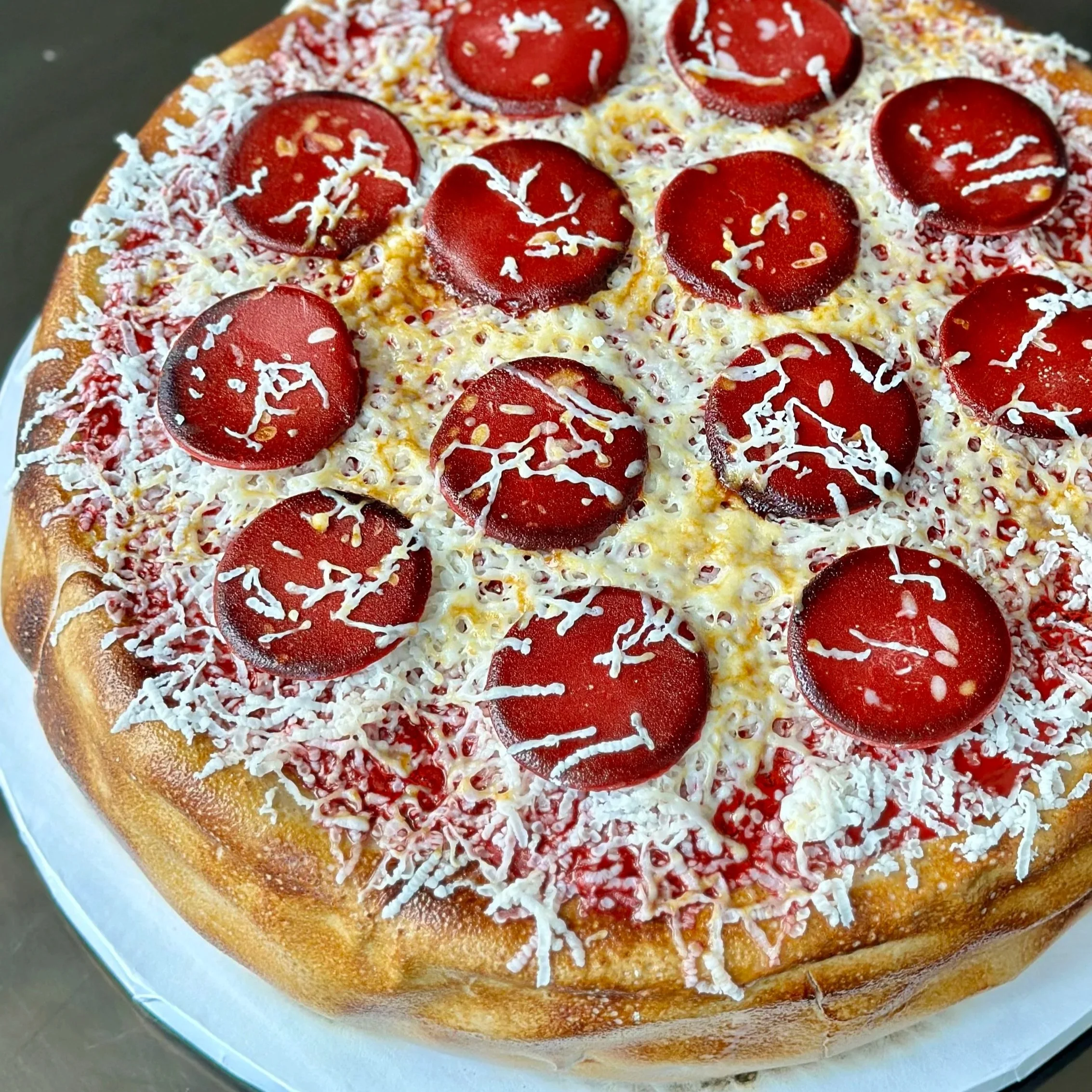 A pizza with pepperoni slices, shredded cheese, tomato sauce, and a golden crust.
