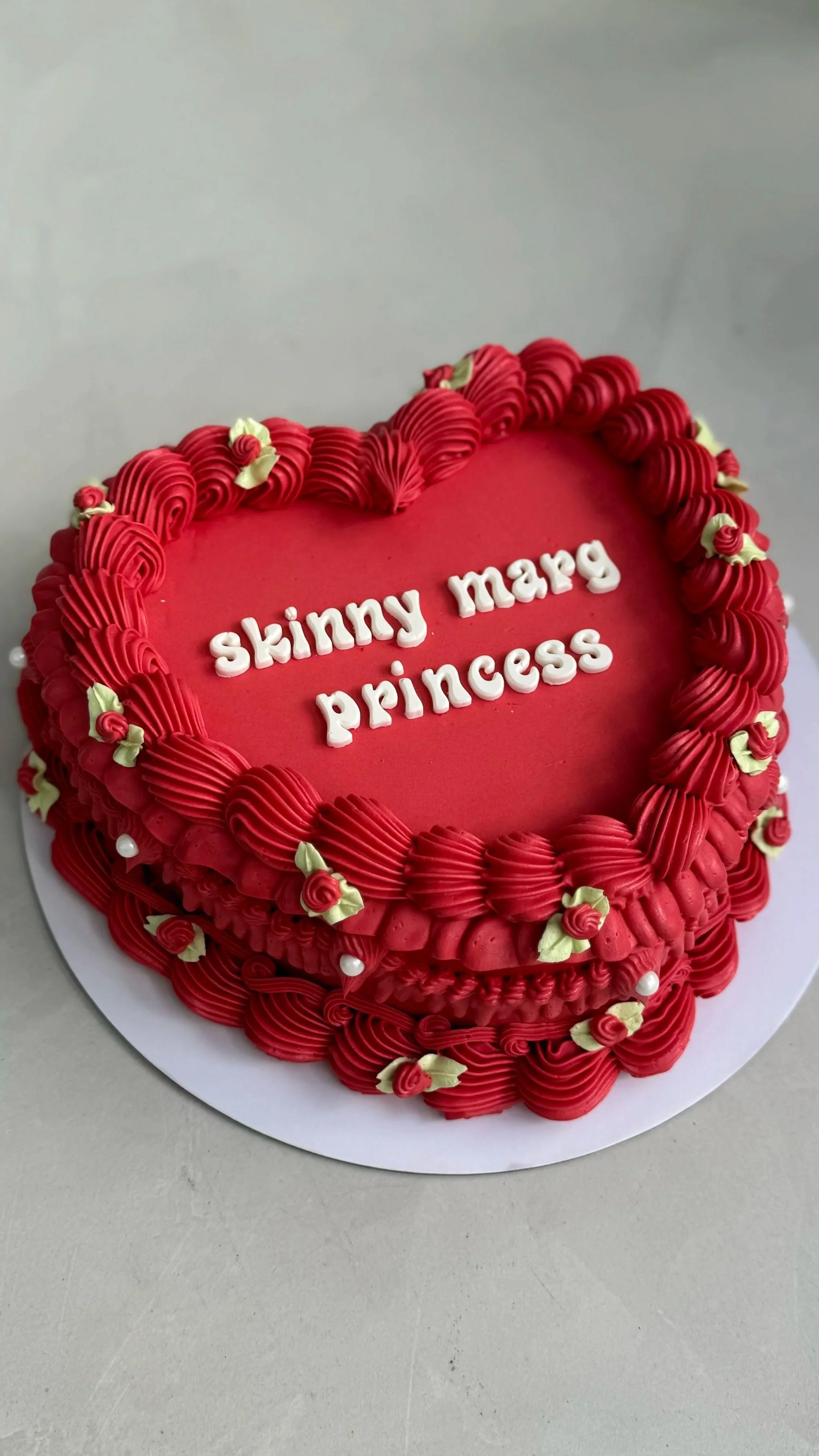 Three bouquets of flower-shaped cupcakes in pastel colors including pink, yellow, and white, decorated with small white flowers, wrapped in iridescent and white tissue paper, placed on a wooden surface.