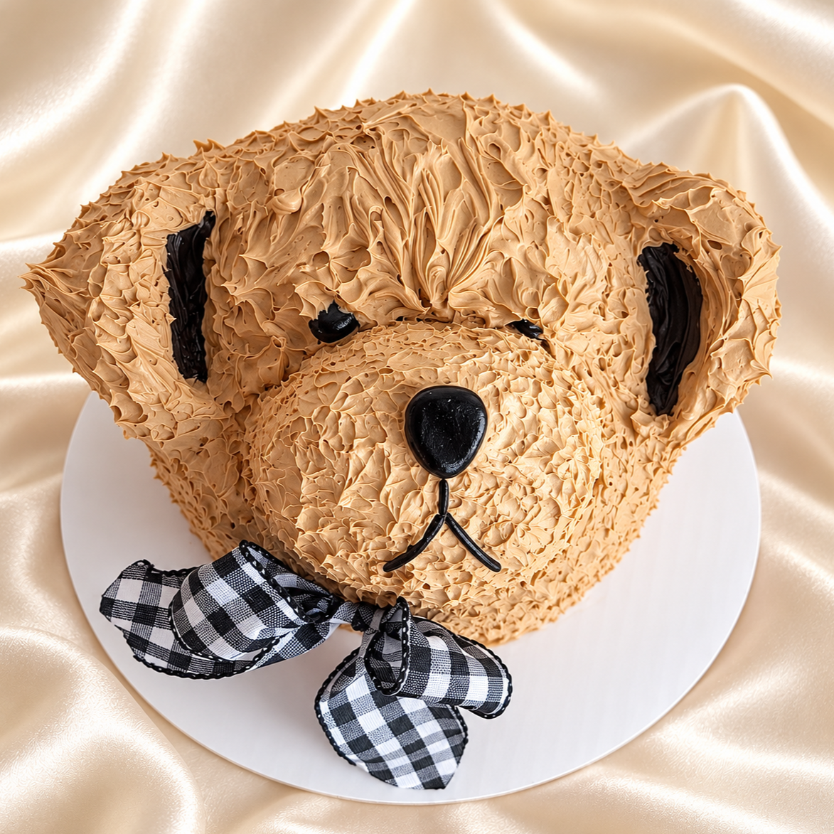Teddy bear shaped celebration cake with piped buttercream fur and a gingham bow