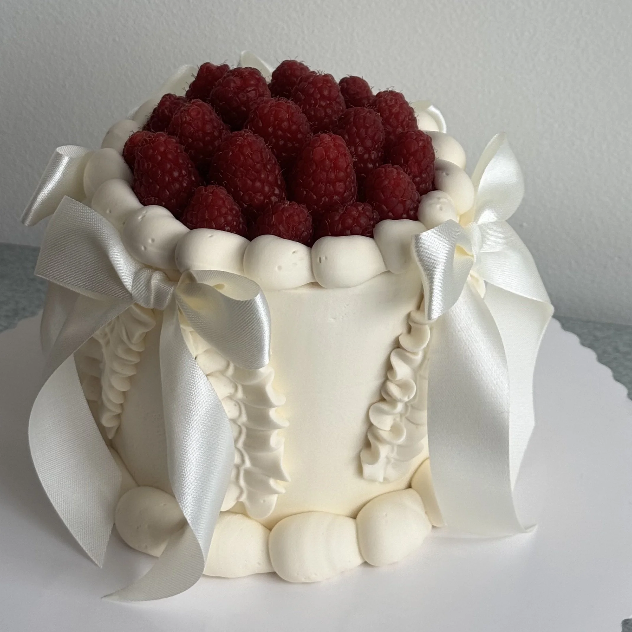 Various decorated Valentine's Day and love-themed cakes on pink cake boards, some with roses, hearts, inscriptions, and initials.