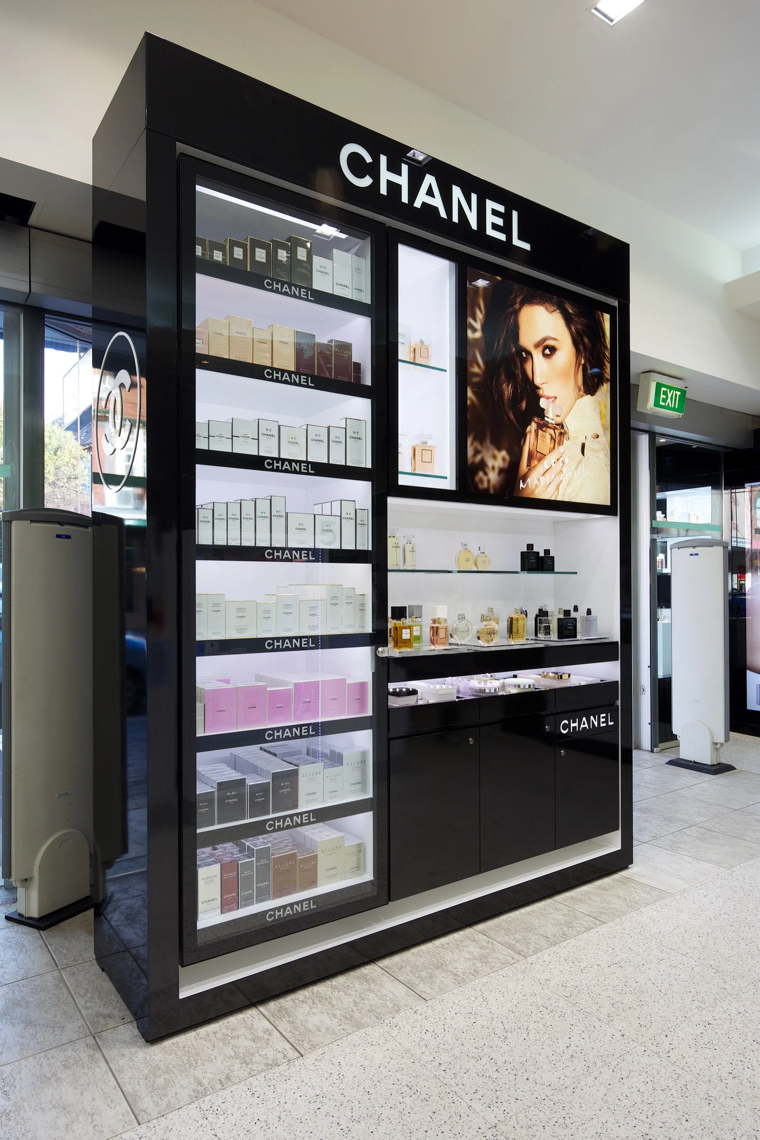 Chanel fragrance wall design with a large advertisement of a woman holding a perfume bottle on the upper right side.