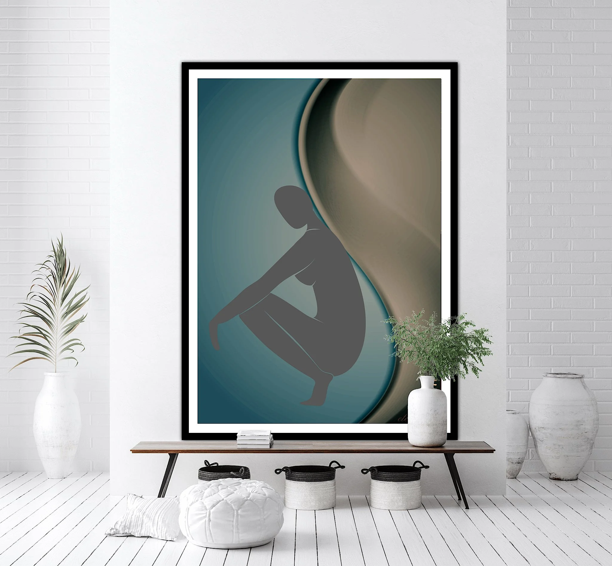 An interior room with a large framed abstract artwork of a silhouette of a woman squatting, in shades of gray, teal, and beige, on a white brick wall. A wooden bench with three baskets, white pillows, and a tall white vase with a leafy green plant.