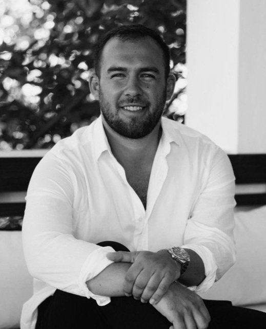 Man in white shirt sitting and smiling in black and white photo