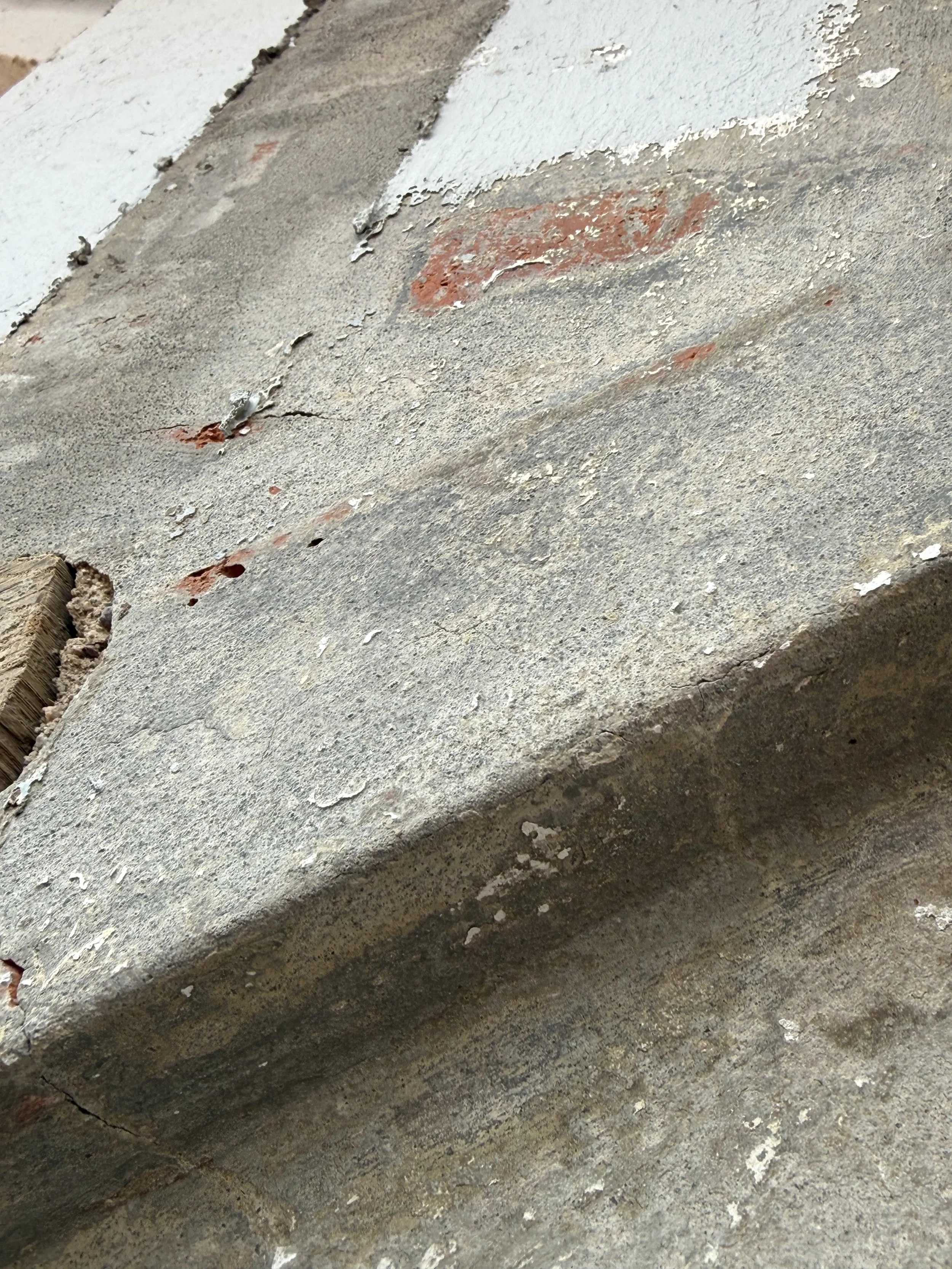 Nahaufnahme eines alten, beschädigten Betonblocks mit Rissen, abblätternder Farbe und Gebrauchsspuren.