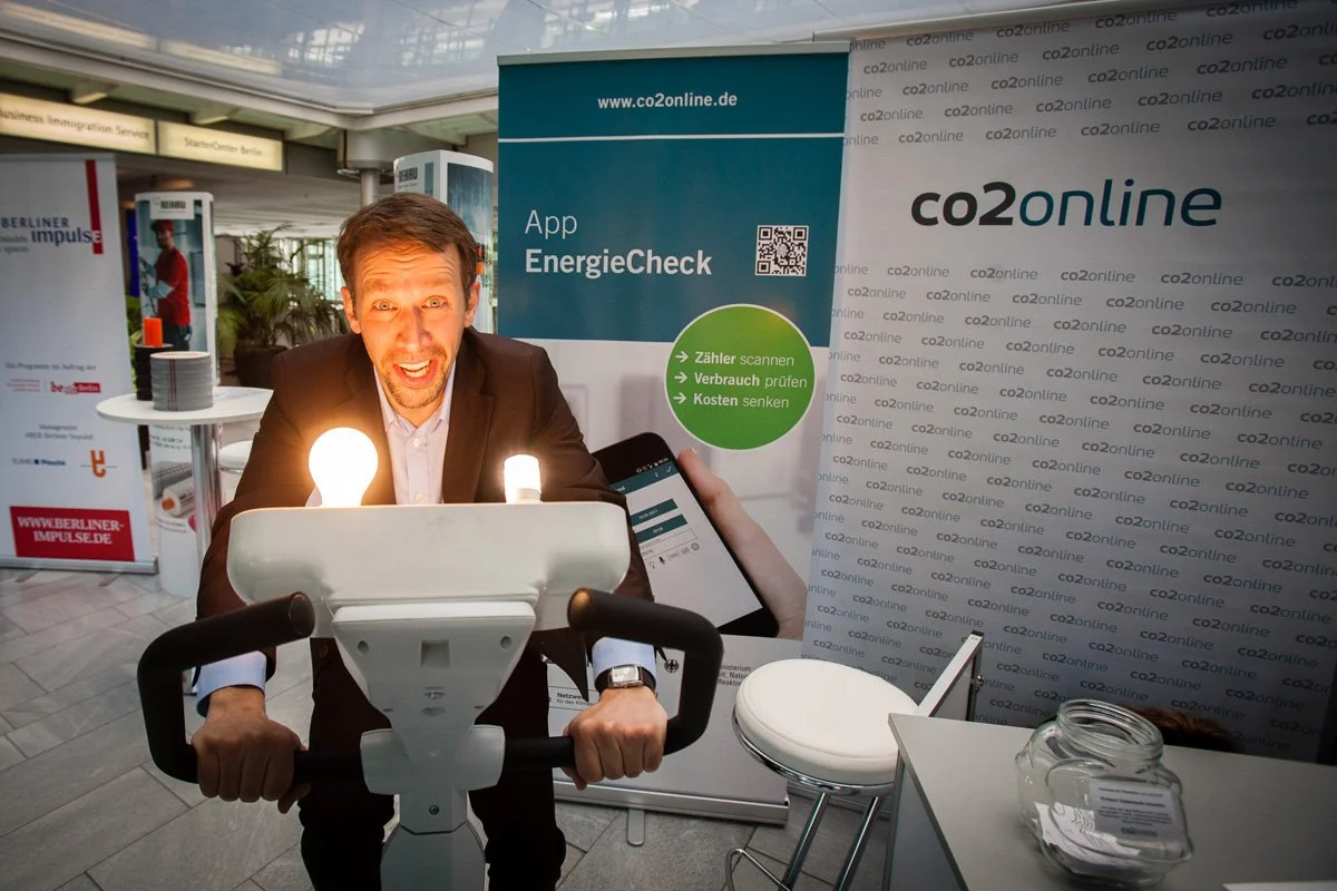 Messefotografie Berlin. Der Geschäftsführer von co2 online auf einer Messe in Berlin auf einem Fahrrad.