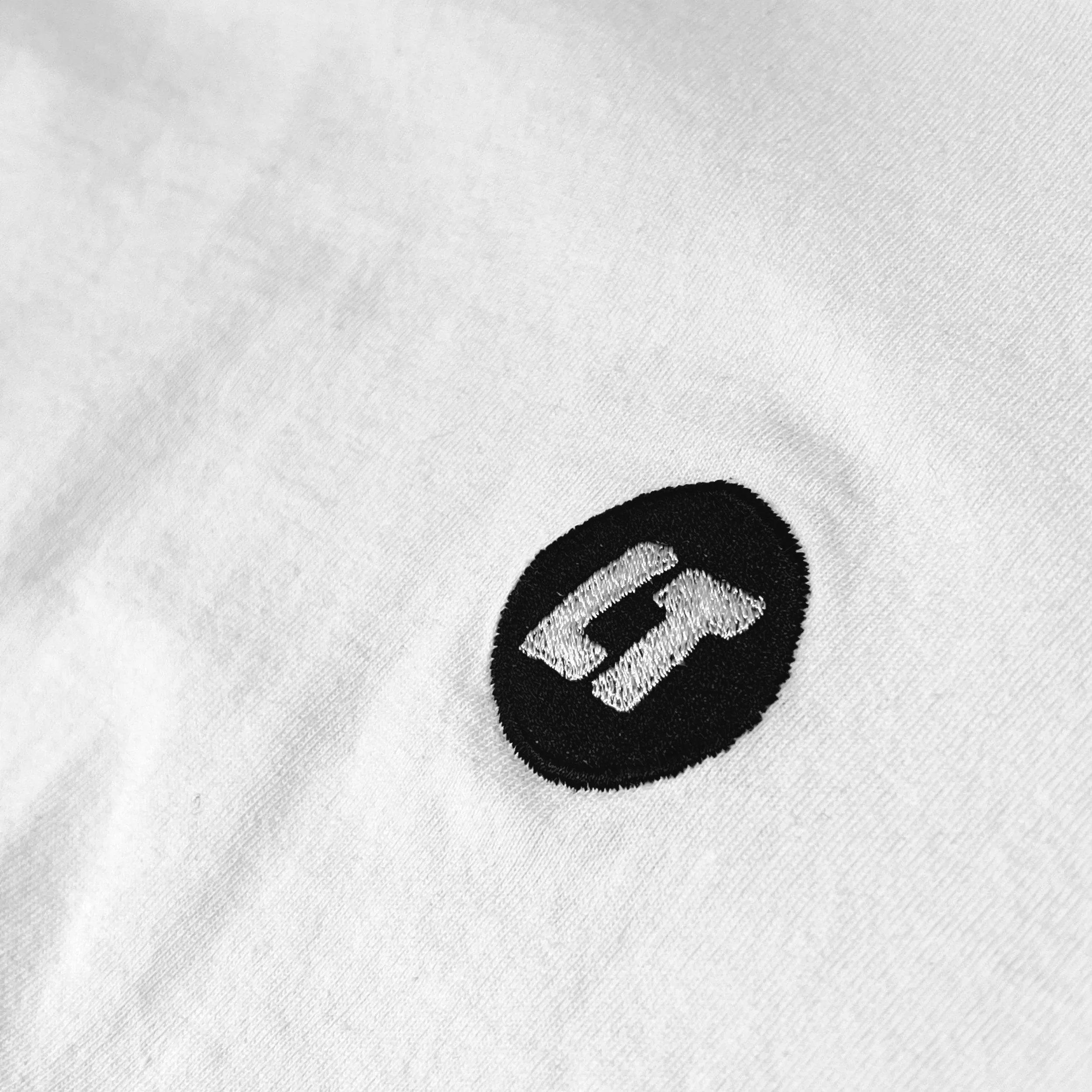 Close-up of embroidered LT badge on Loose Tuesday logo tee