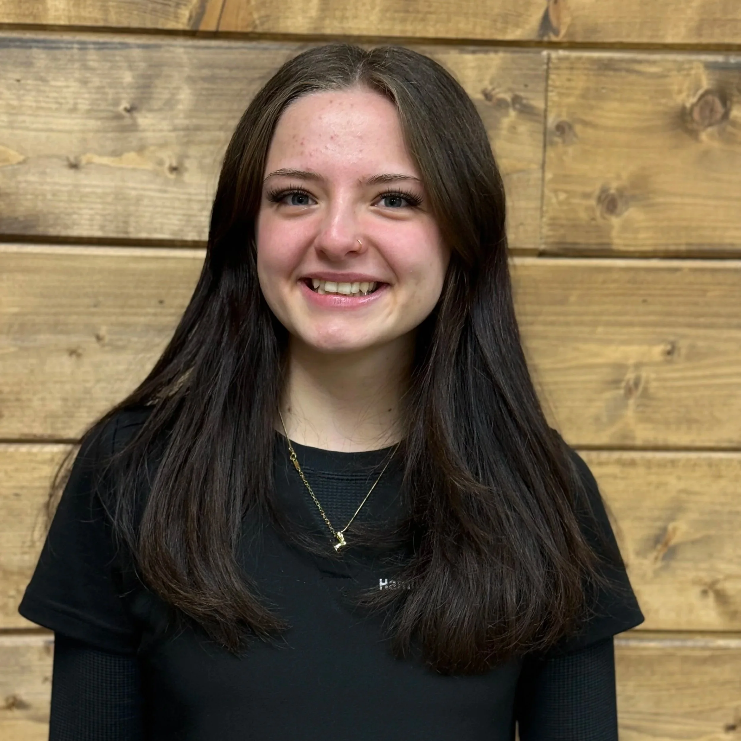A cute, fluffy dog with curly fur looking at the camera against a dark background.