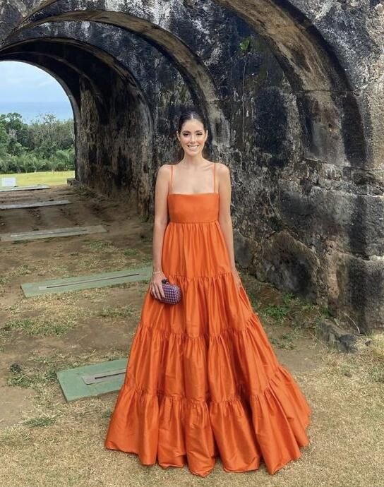 Woman in orange dress standing in historical stone archway