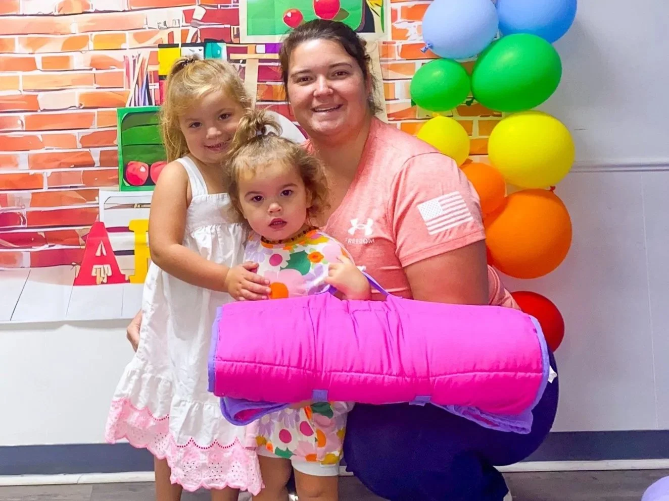 A mother and two young daughters with a nap mat at Little Blessings