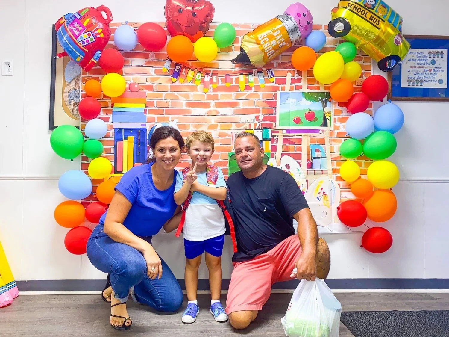 A Little Blessings family smiling in front of a colorful balloon arch