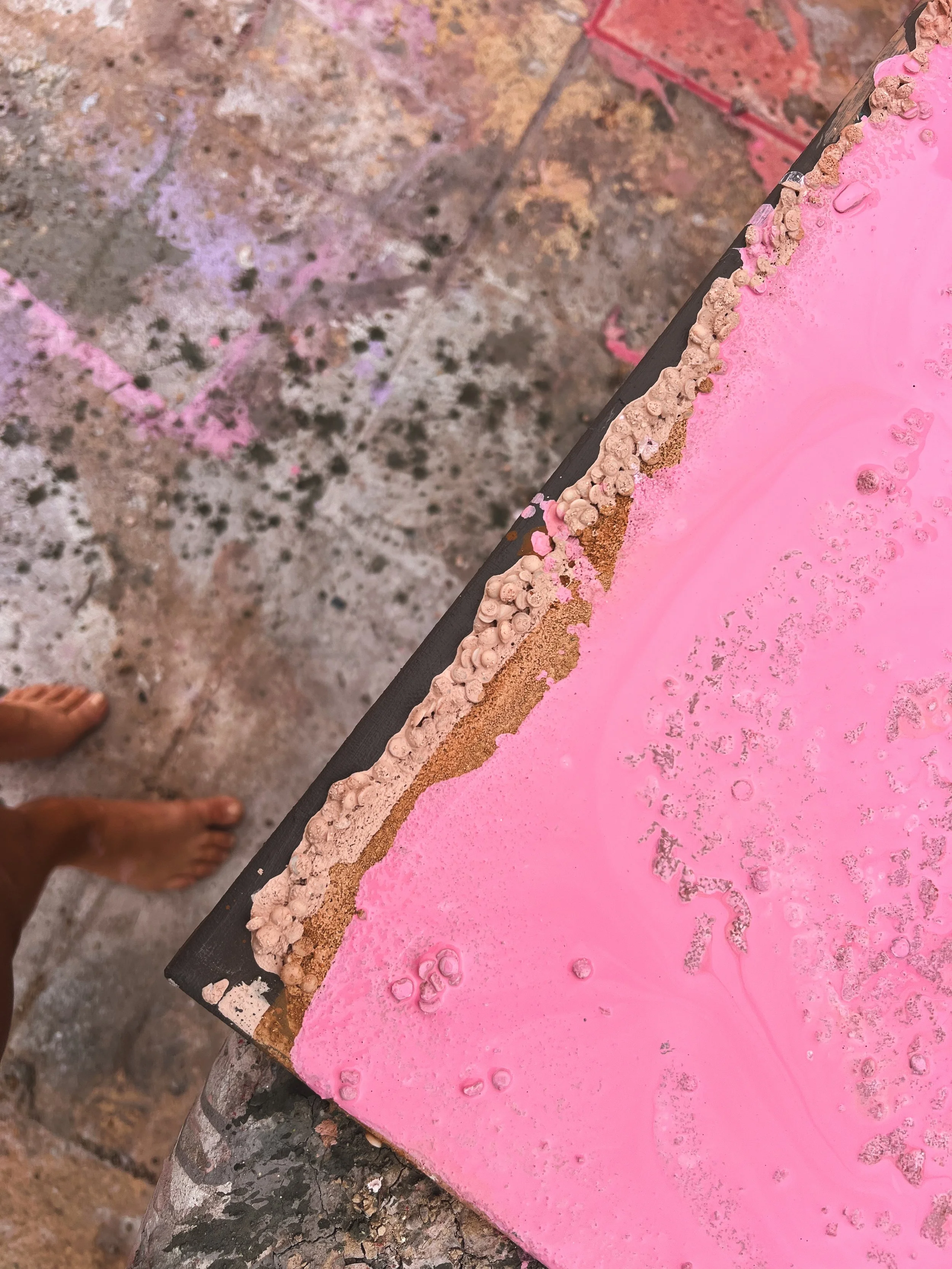 Close-up of a weathered pink-painted surface with chipped edges and textured peeling paint.