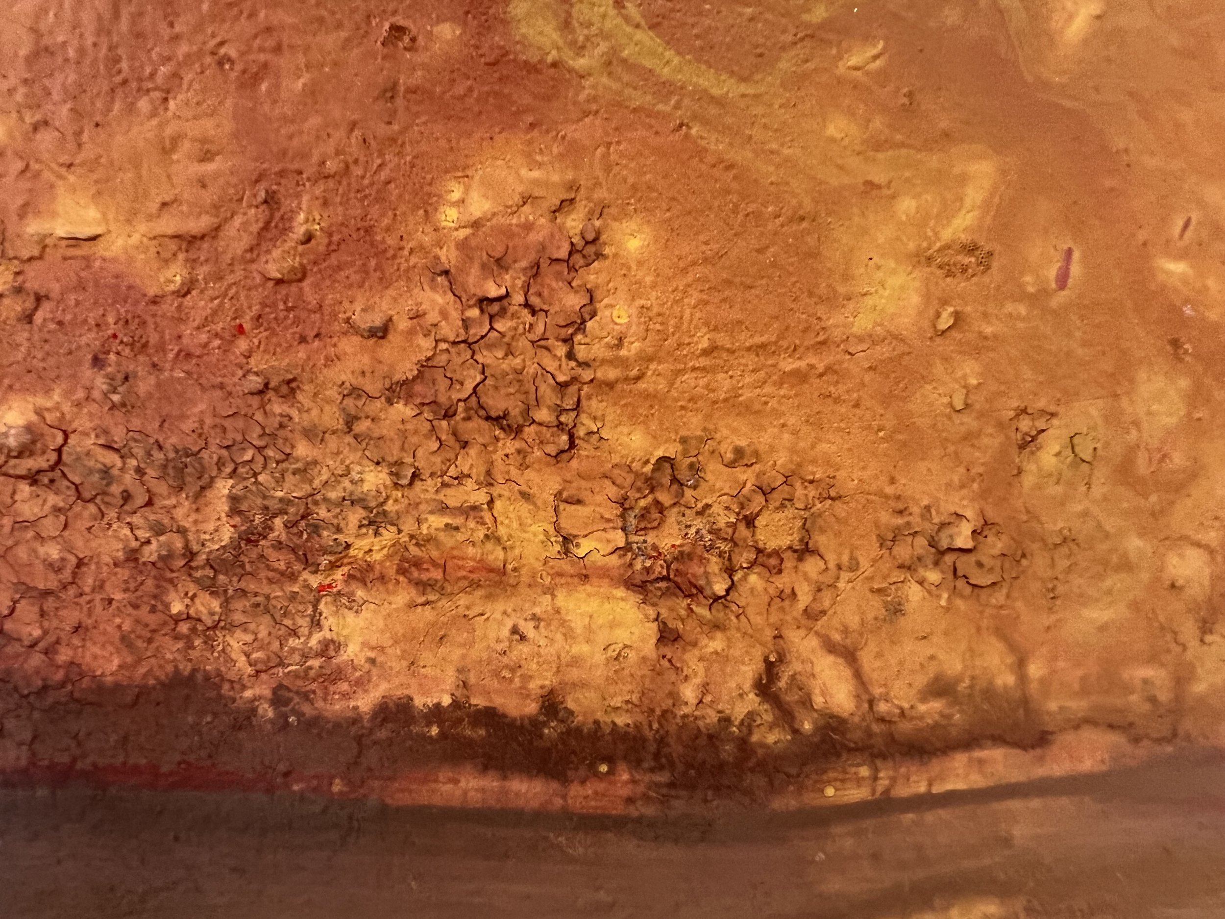 Close-up of a rough, cracked orange-brown earthen surface with layered texture