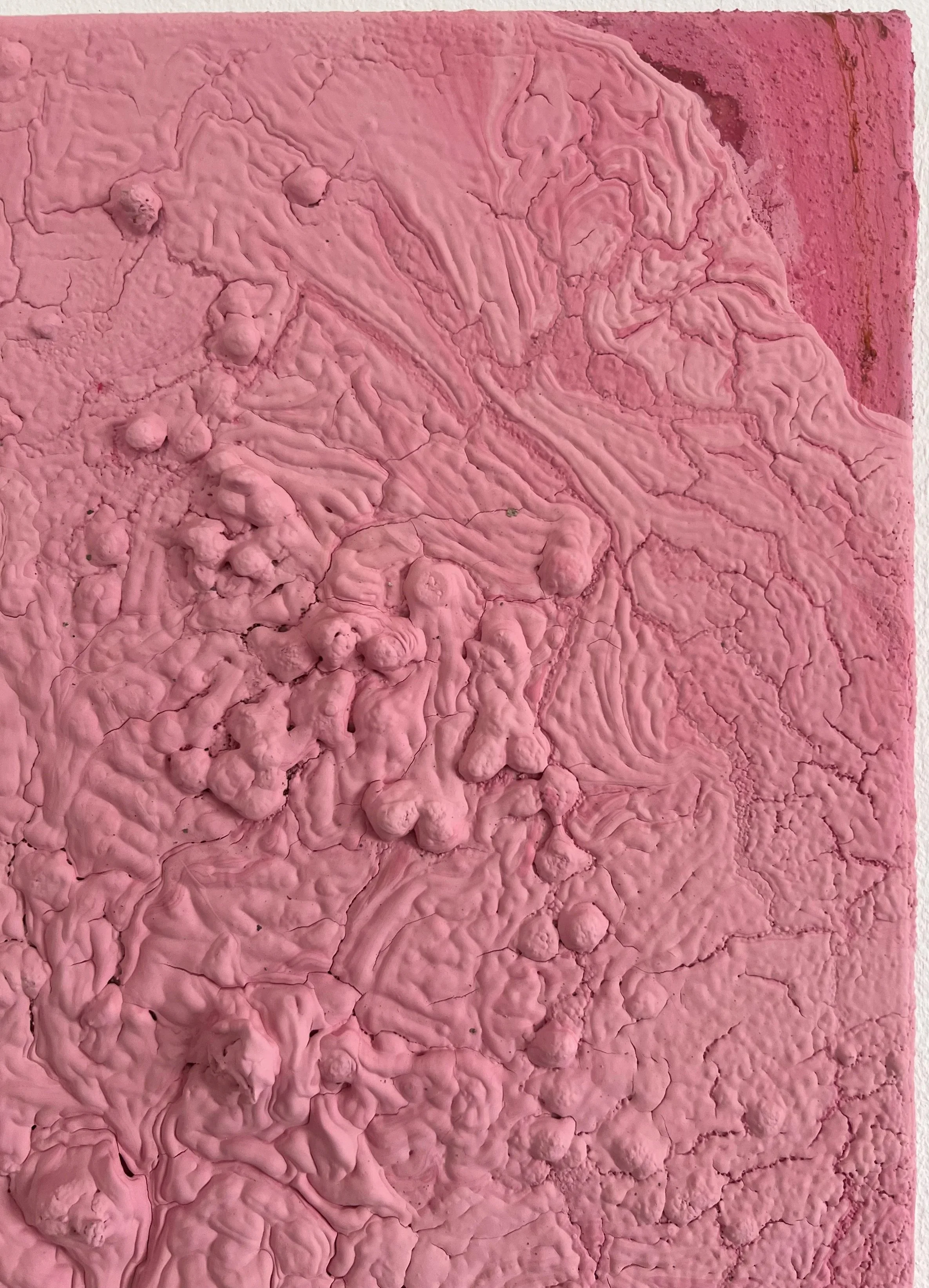 Close-up of textured pink plaster or paint with rough cracks and raised swirls