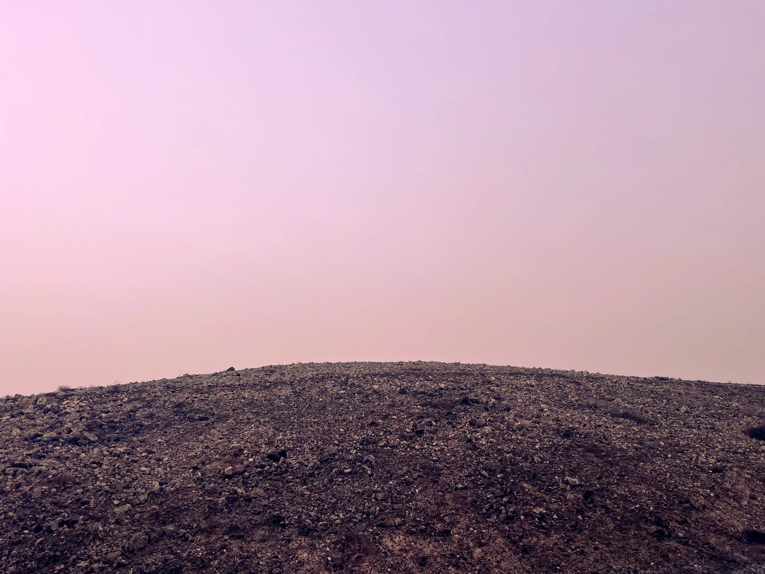 Rocky barren hillside beneath a soft pink and purple sky