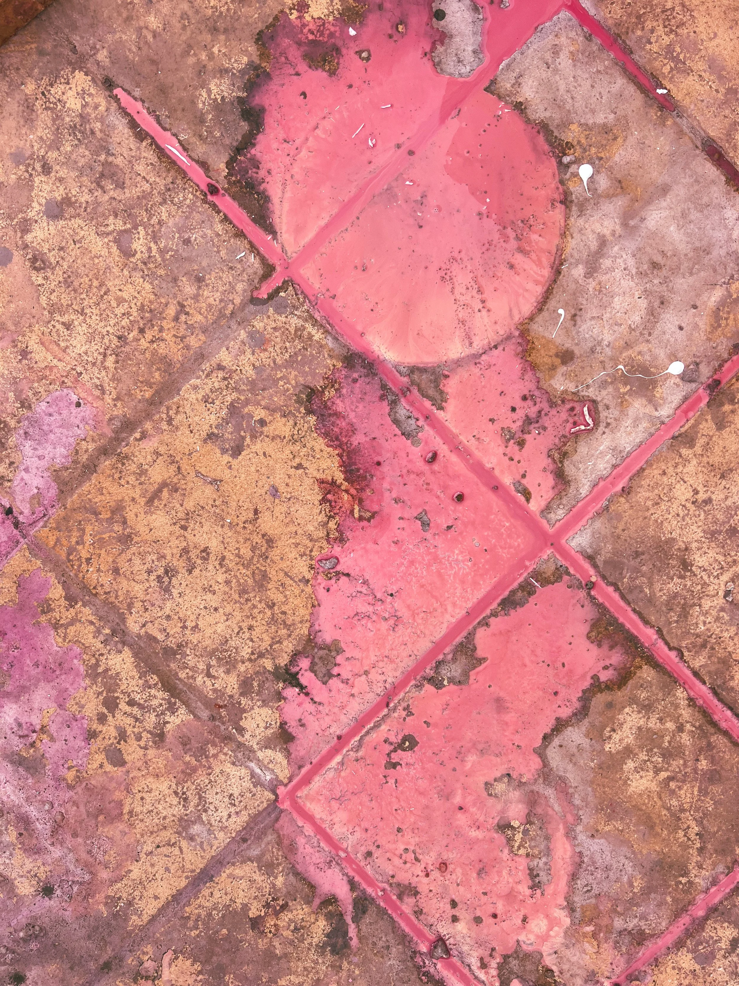 Close-up of weathered pink and brown paint peeling across a rough surface