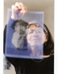 Person holding a transparent glass or plastic sheet in front of their face, creating a double image.