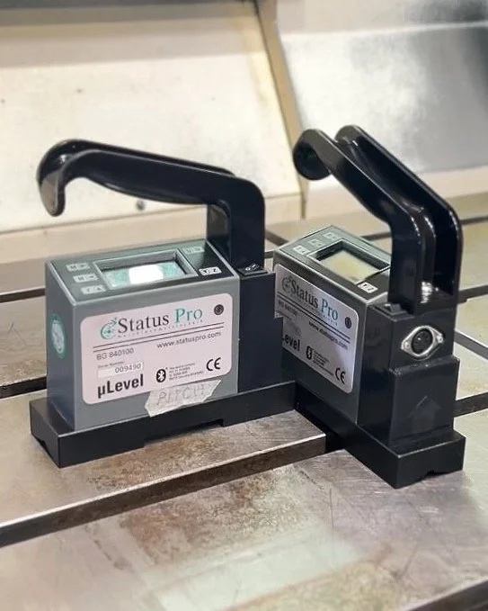 Two digital device testers labeled 'Status Pro,' with black handles and digital screens, placed on a wooden surface.