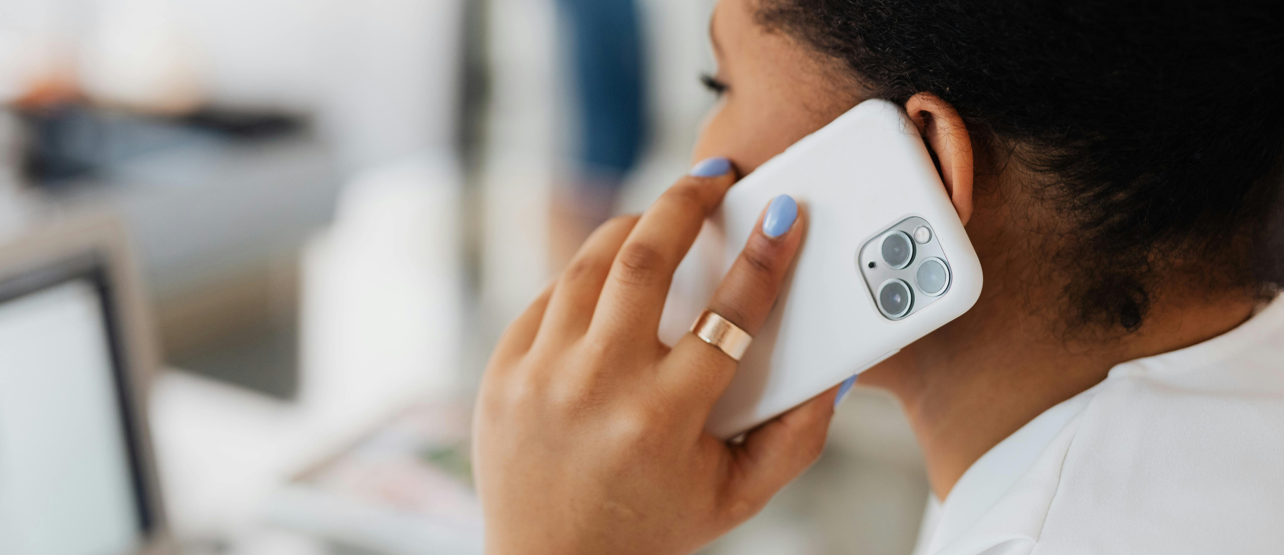 Person talking on a white smartphone in an indoor setting.