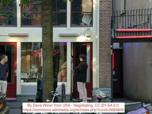 A prostitute and a potential client negotiate through a part-opened door in Amsterdam's Red-Light District
