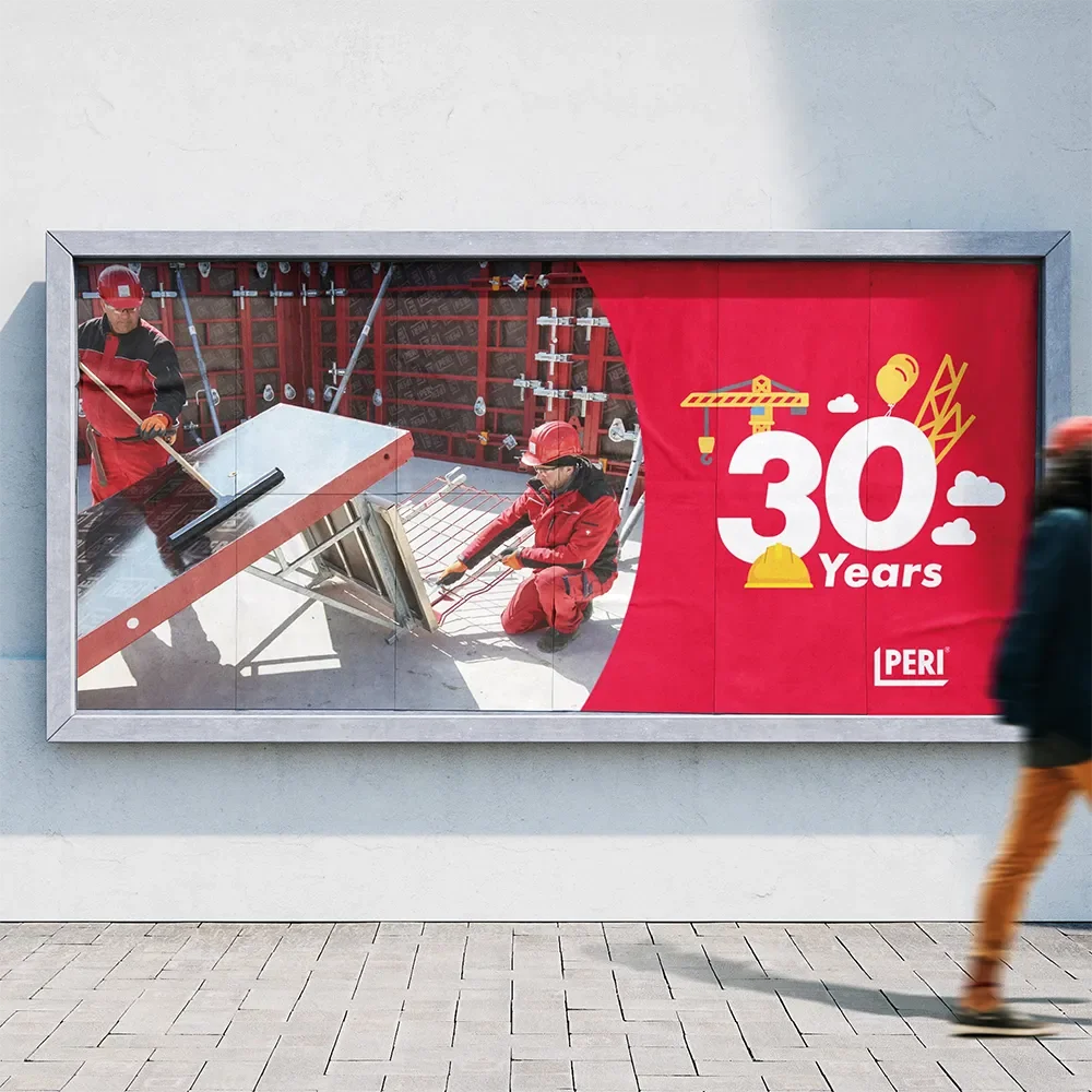 En reklamskylt som firar Peri:s 30-årsjubileum, med en bild av två personer i rött arbetskläder och hjälmar som arbetar med en byggnation.