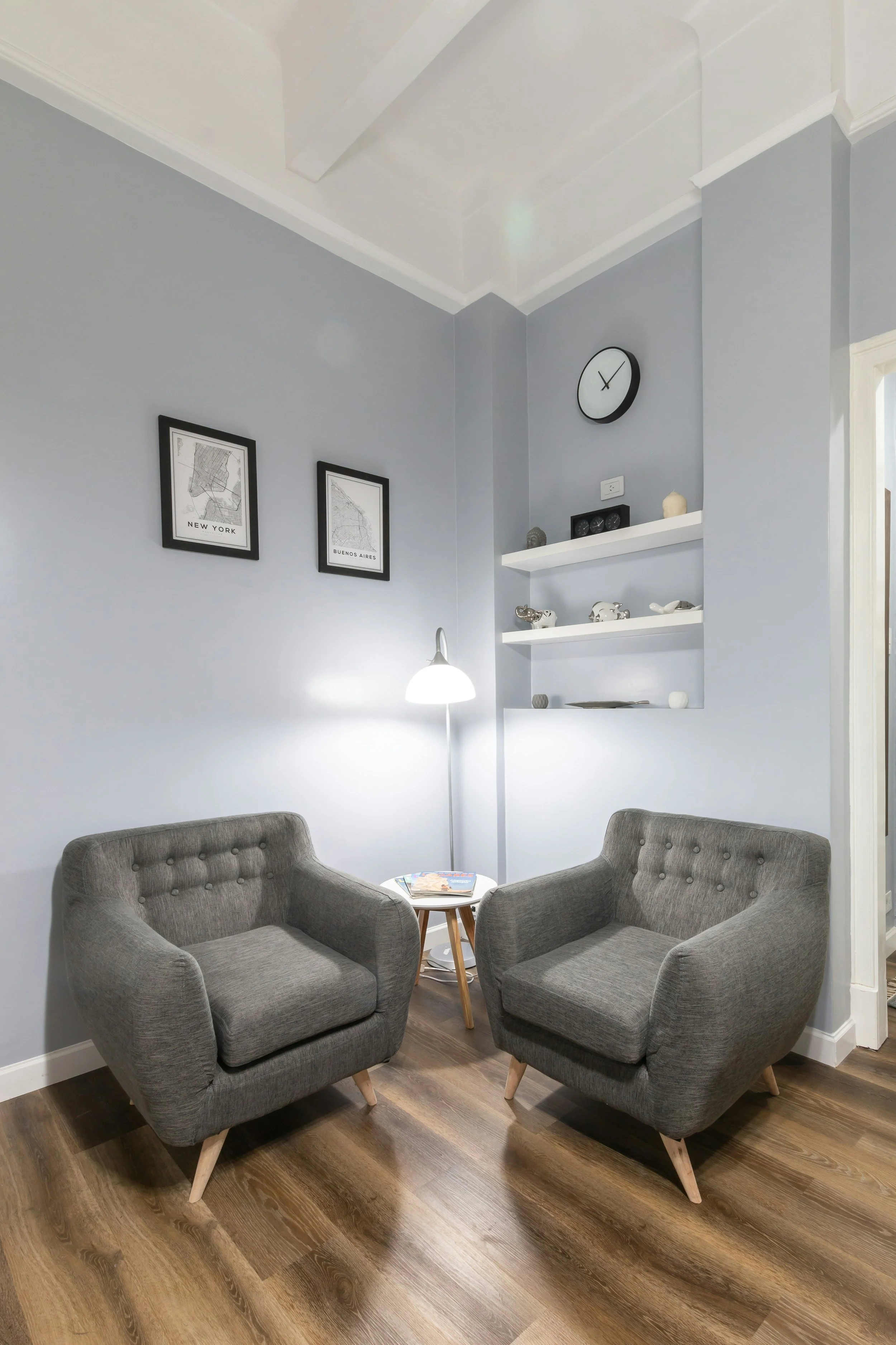 Small practice waiting room with gray armchairs and a side table — the kind of space Check-In App's QR code replaces a receptionist for