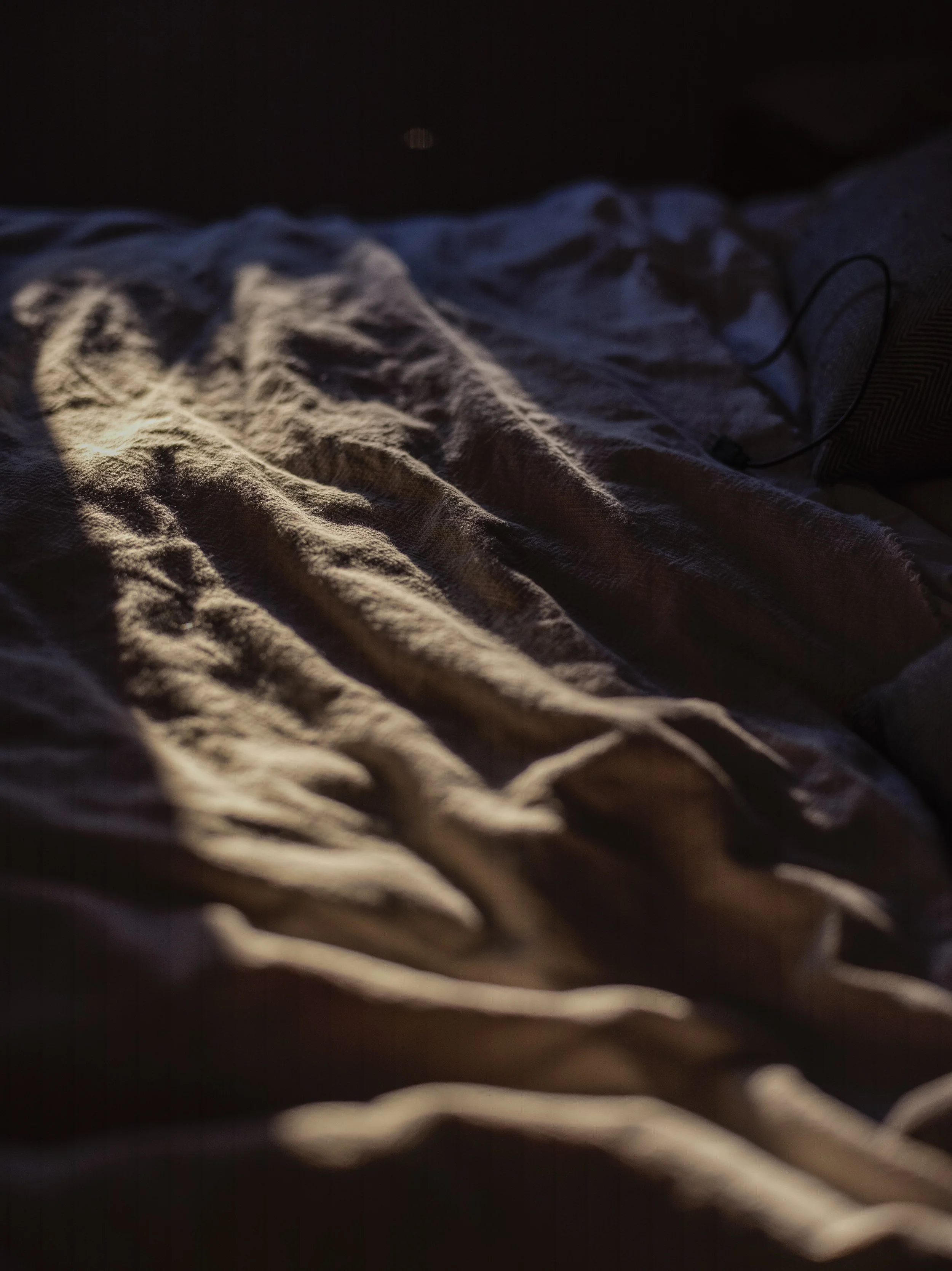 Crinkled bedsheet or blanket with soft lighting and shadows.