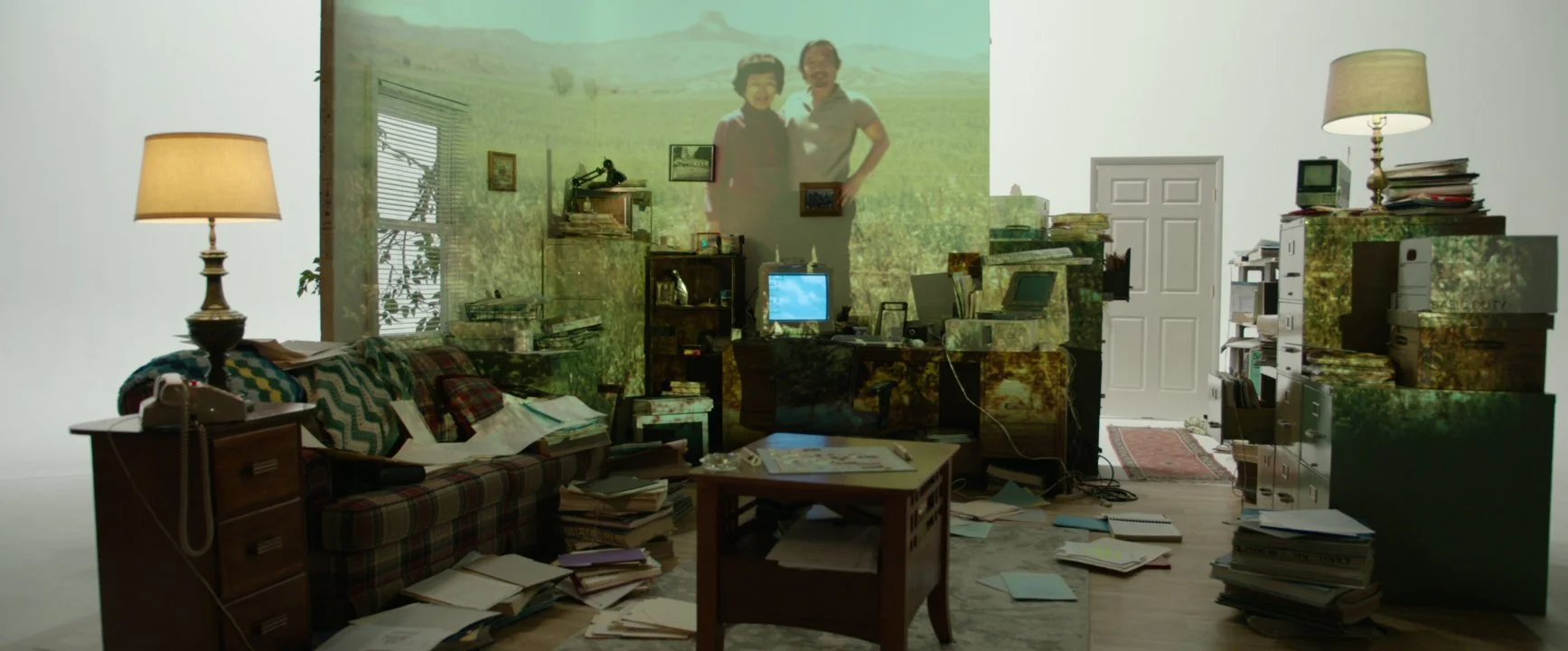 A set reconstructing Kiyoshi's apartment, with a family photo projected on the wall