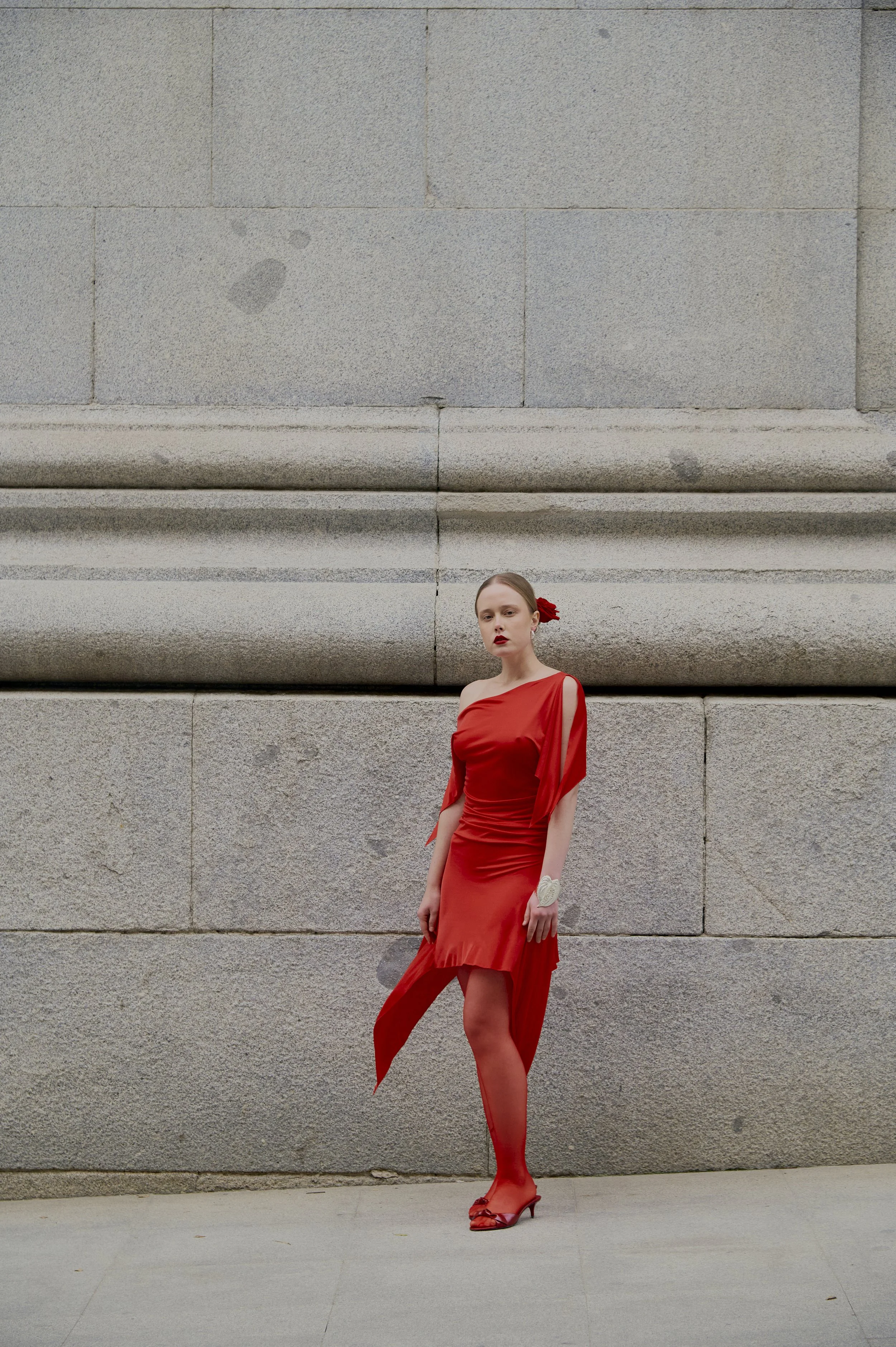 Red sculptural draped dress with asymmetrical sleeve and couture silhouette