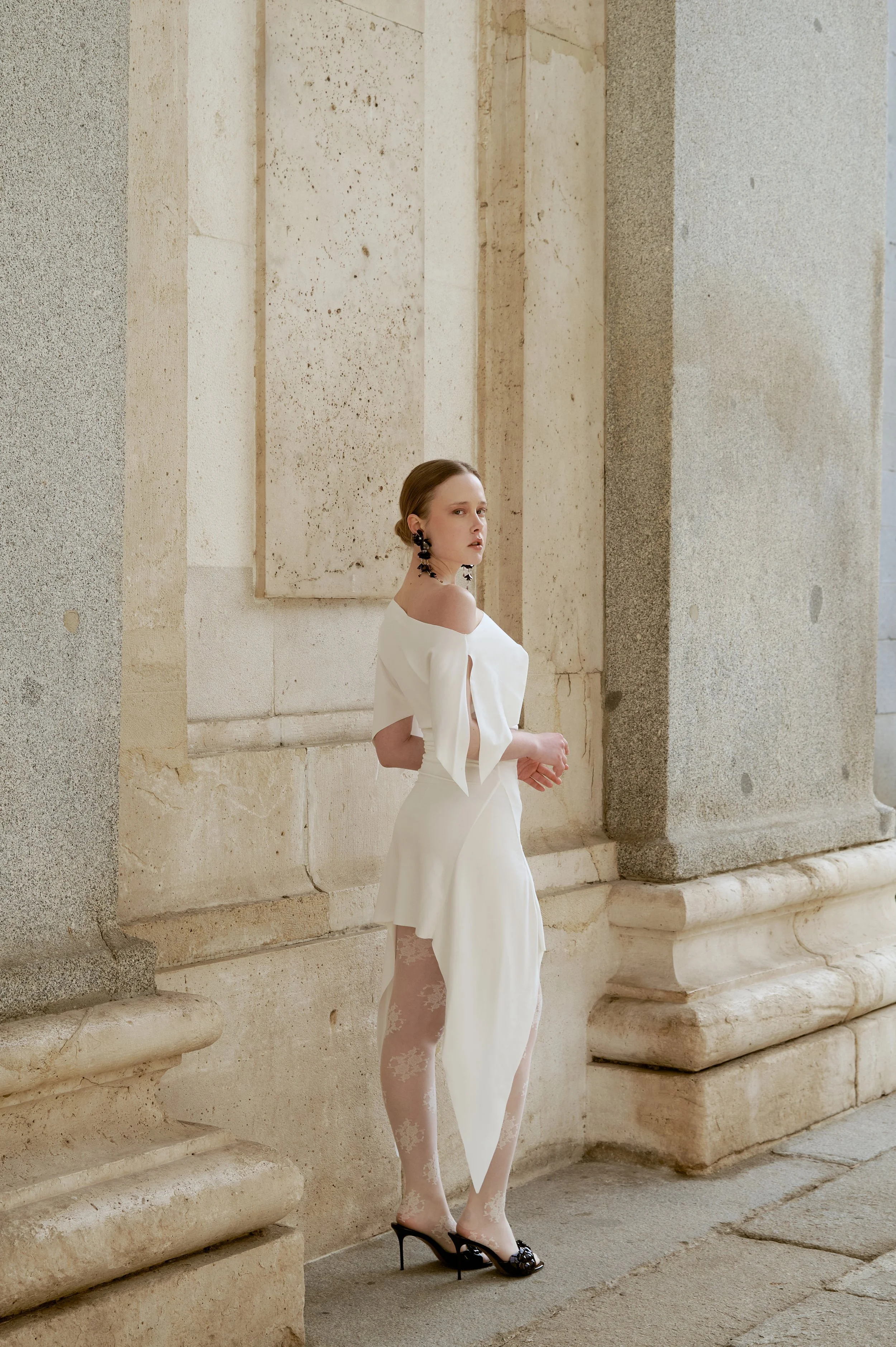 Elegant white jersey dress with asymmetrical drape and refined couture lines
