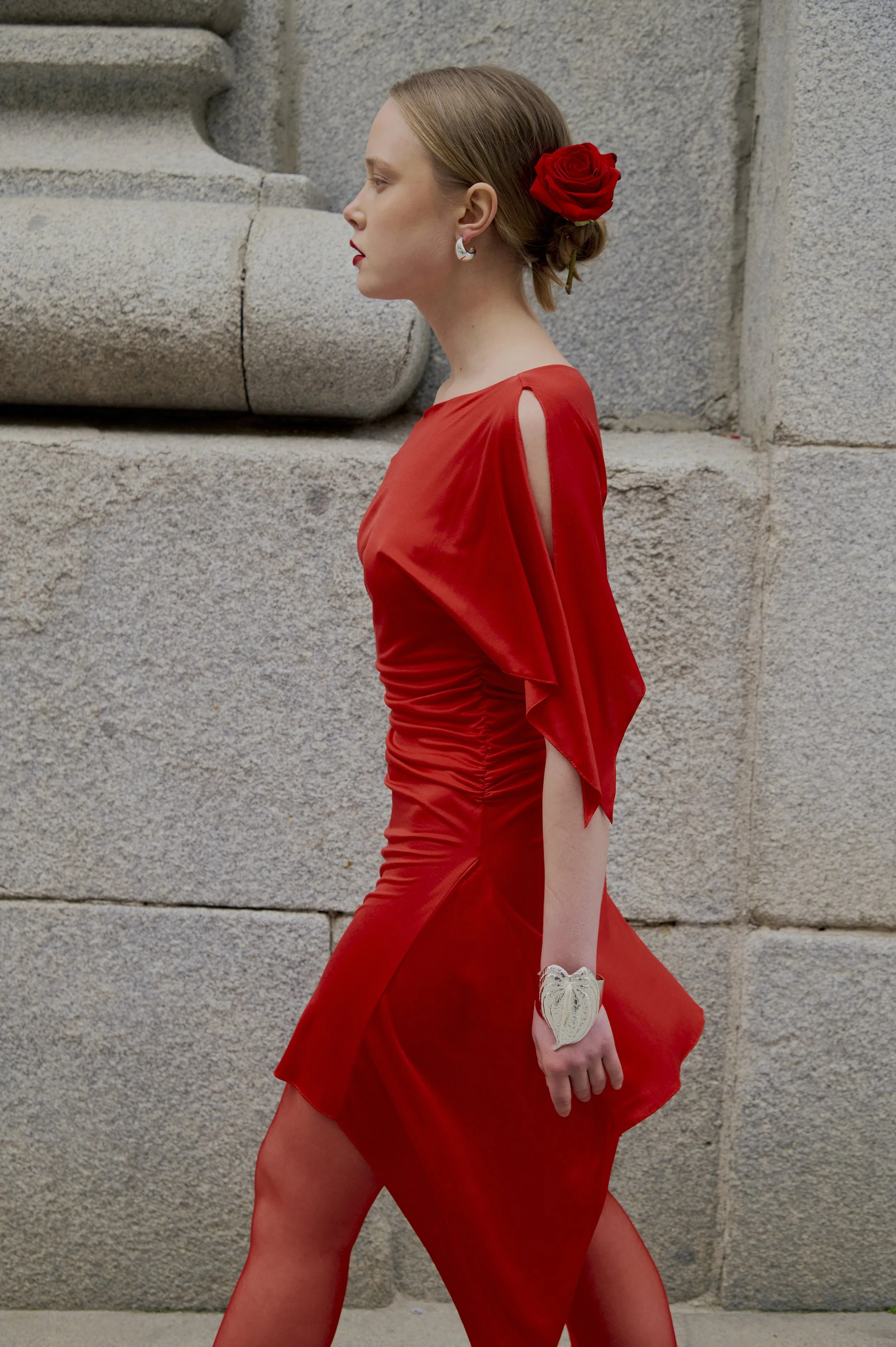 Couture red dress with fluid draping and asymmetric sleeve detail