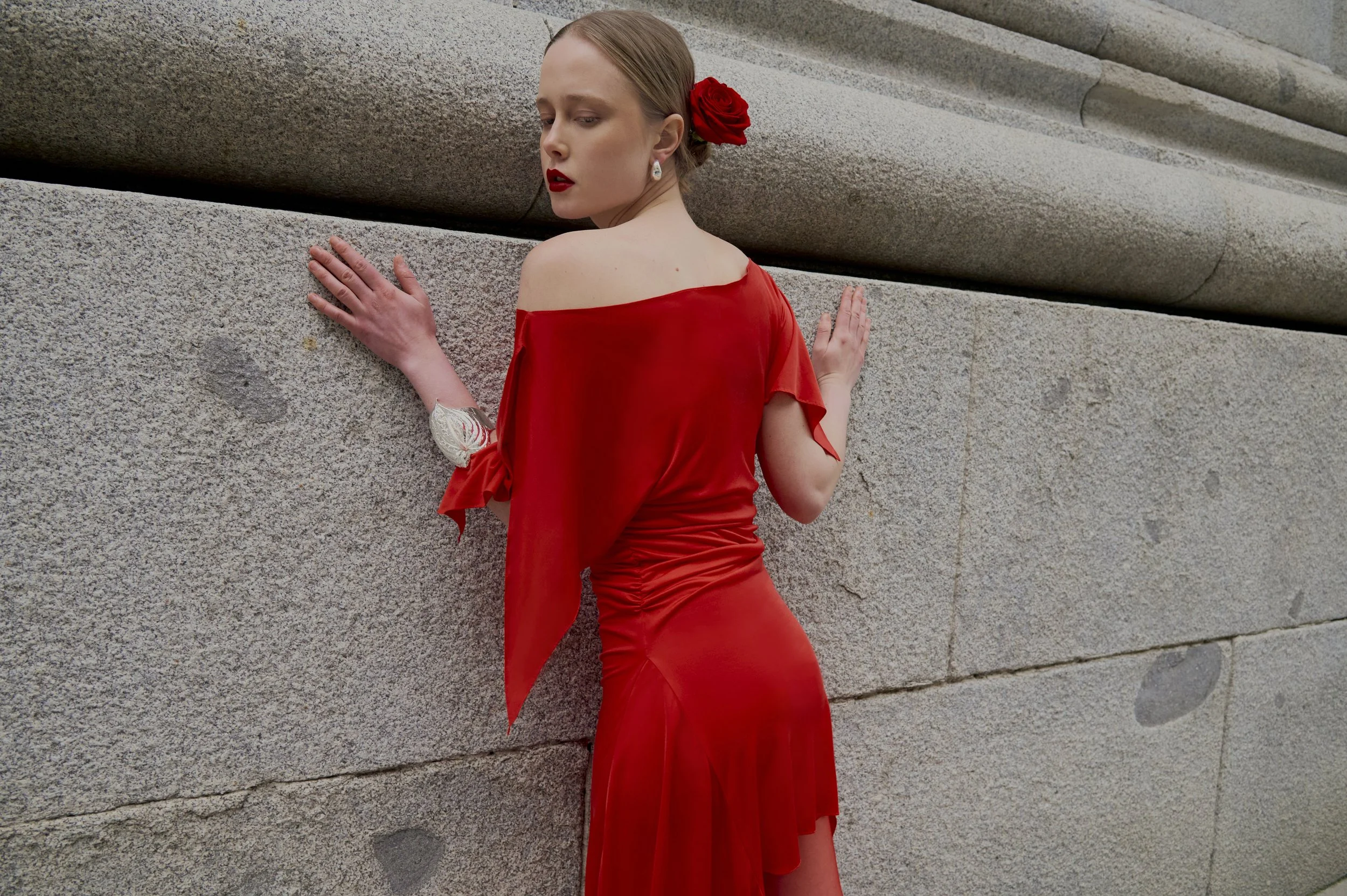 Red sculptural draped dress with asymmetrical sleeve and couture silhouette