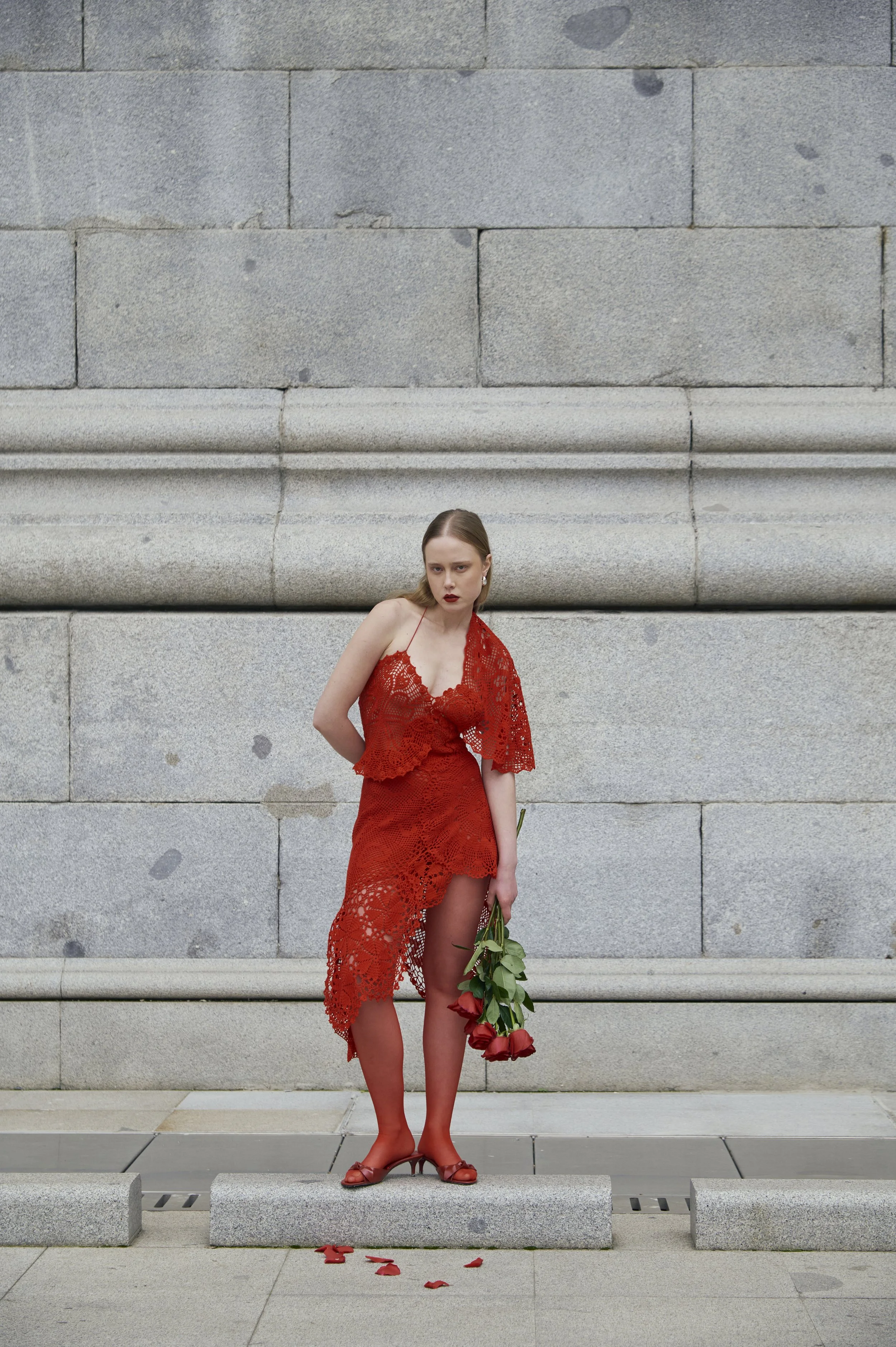 Red crochet couture dress with asymmetrical silhouette and artisanal lace texture