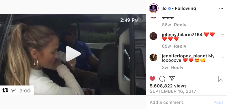 A woman with a high ponytail drinking from a bottle while sitting on a bus, with a man in the background.