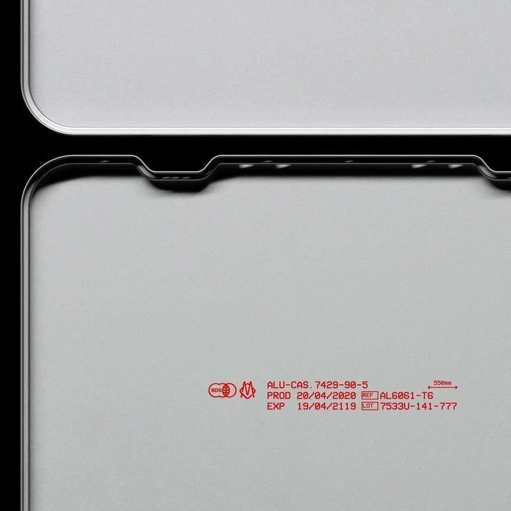 Close-up of an electronic device, possibly a laptop, with red manufacturing and safety markings on the bottom surface.