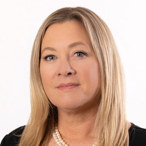 An elegant blonde woman smiling with a pear necklace and a white background