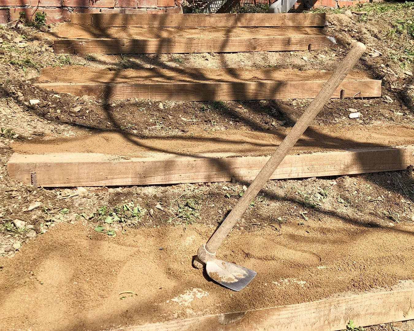 la imagen muestra una herramienta de jardinería sobre unas escaleras de traviesas de pino recien colocadas