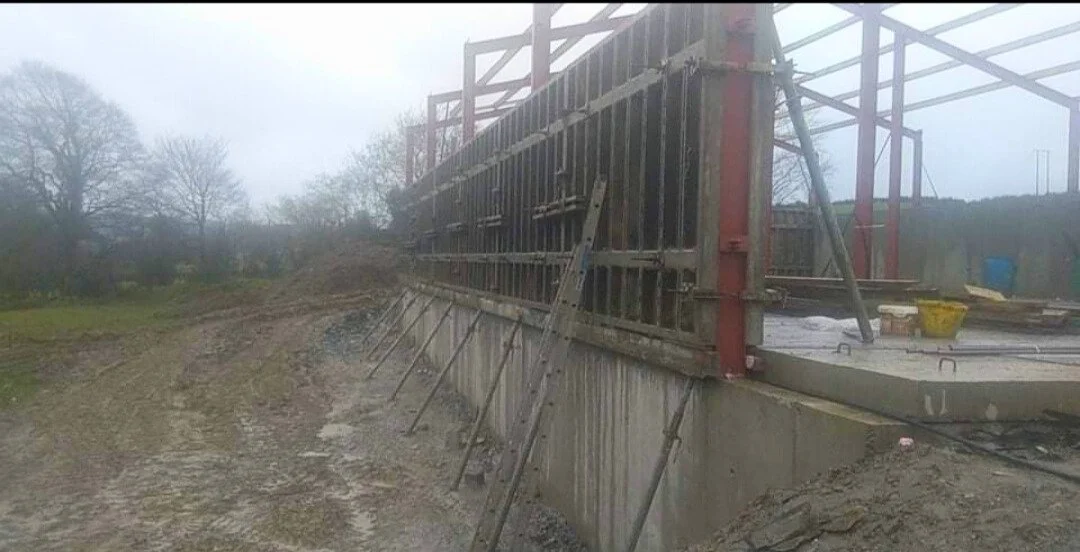 Construction site with concrete foundation and metal scaffolding framework for a building.
