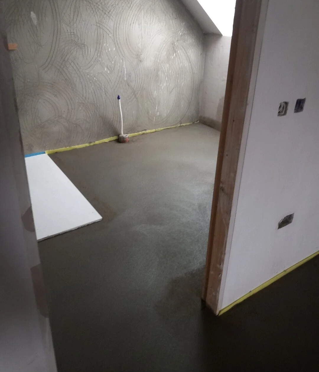 Room under construction with an unfinished wall, electrical box, and a level on the floor.