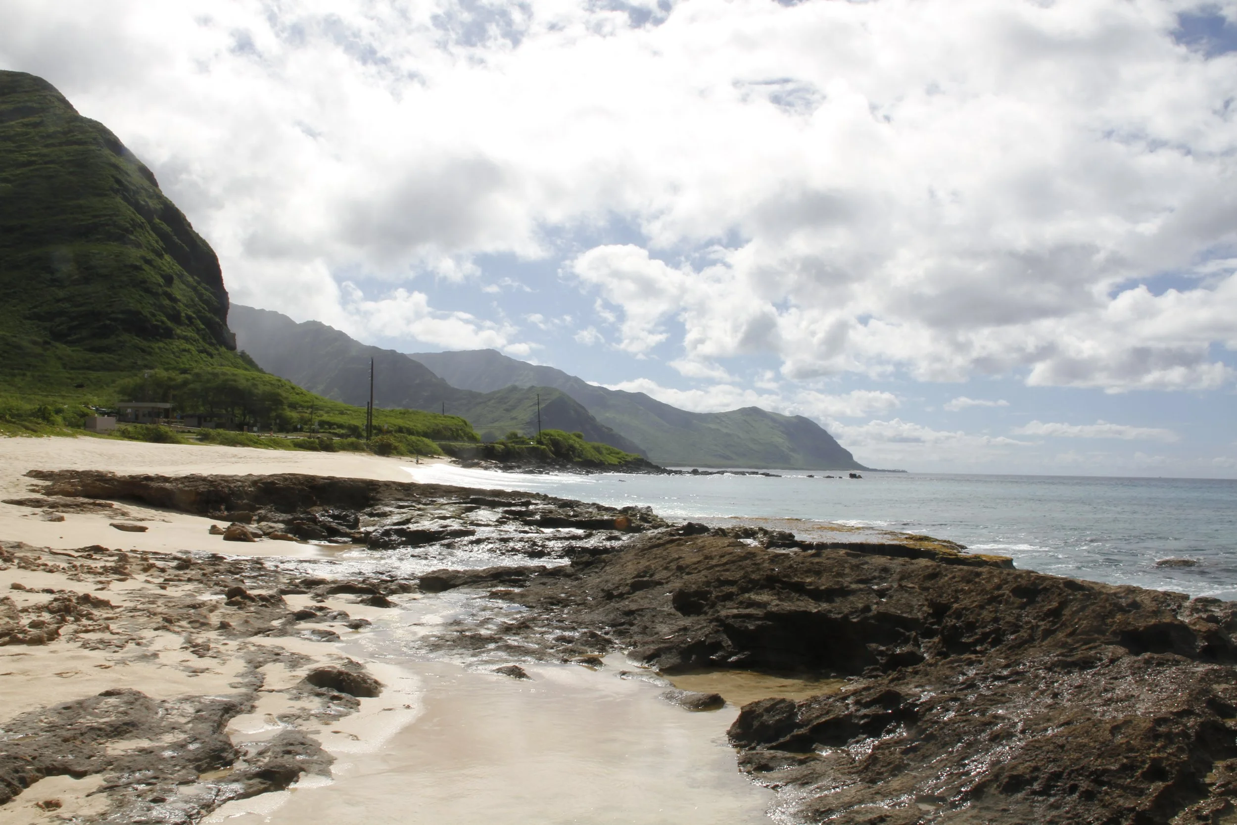 Rocky beach with mountains and ocean, cloudy sky. Hawaii film, video, photo production service