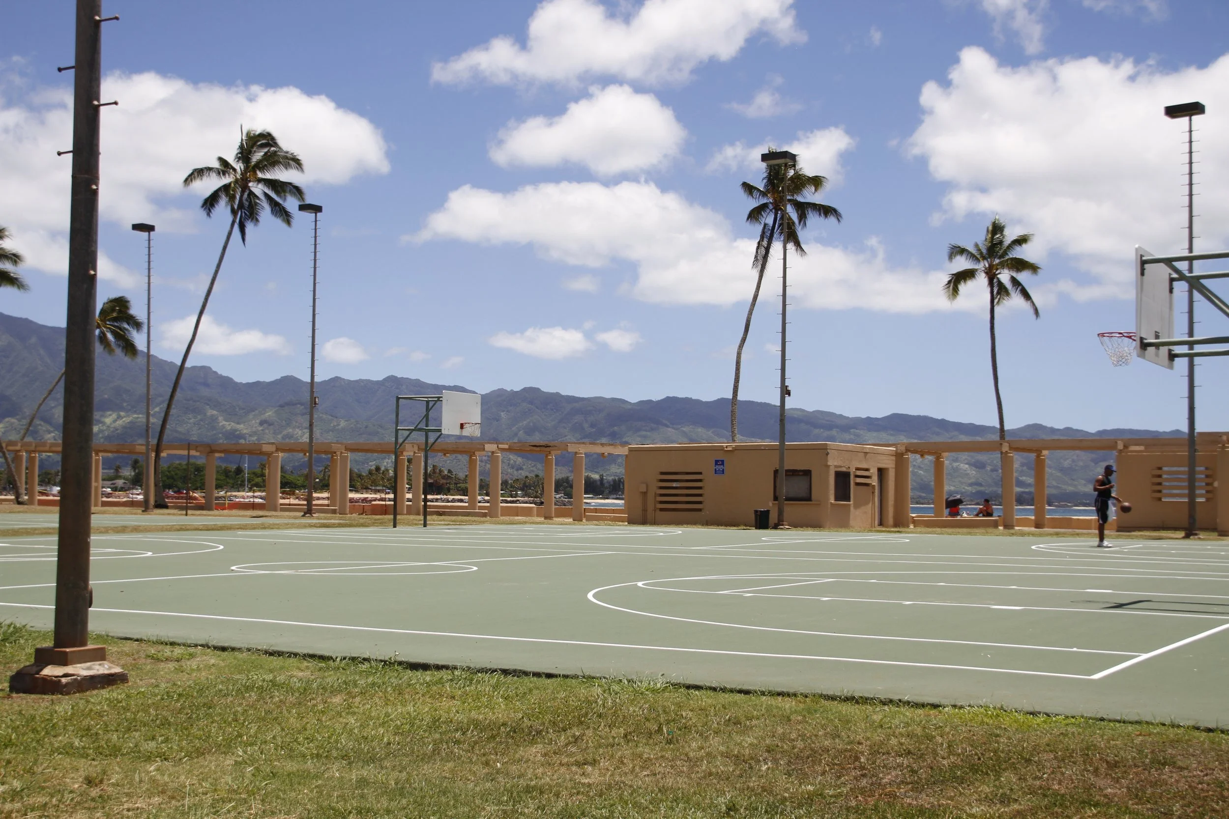 Outdoor basketball court with palm trees and mountains in the background. Hawaii film, video, photo production service
