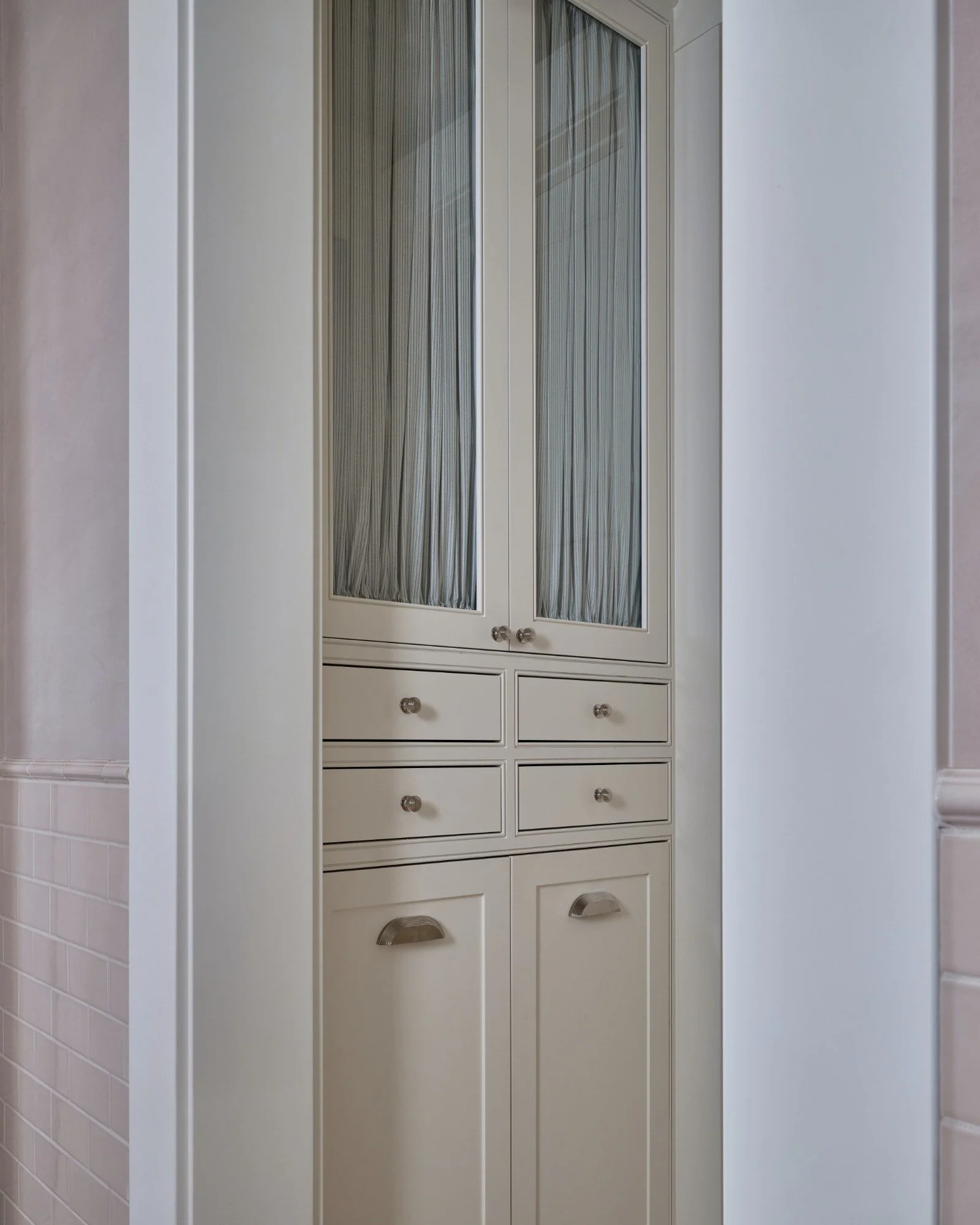 -built-in white kitchen cabinet with glass-paneled doors and small drawers beneath, situated between two walls