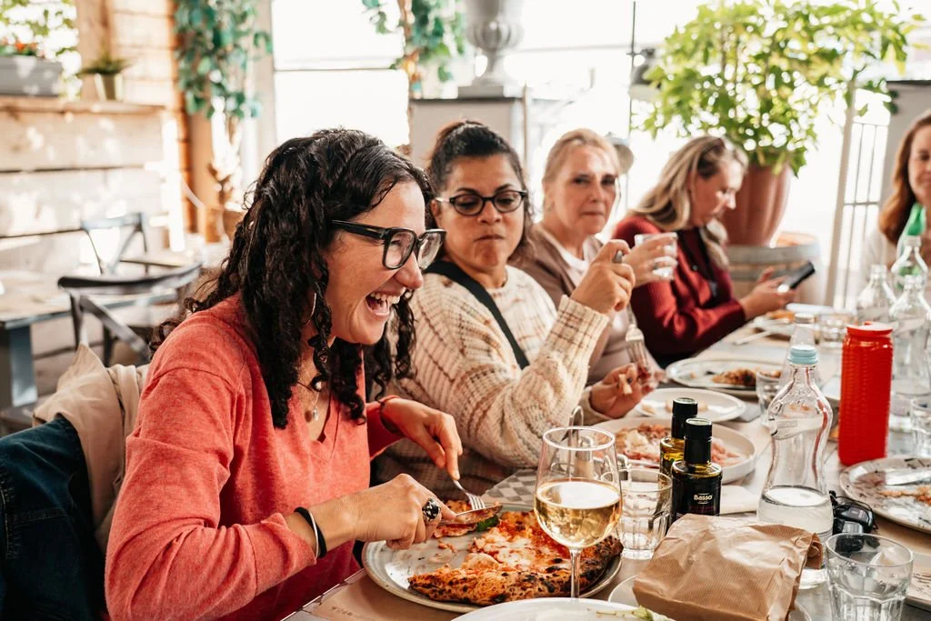 Women on a Bible Study Live trip laughing together over a shared meal in Italy