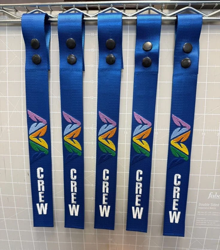 Blue fabric wristbands with a colorful rainbow design and the word 'CREW' written vertically in white.