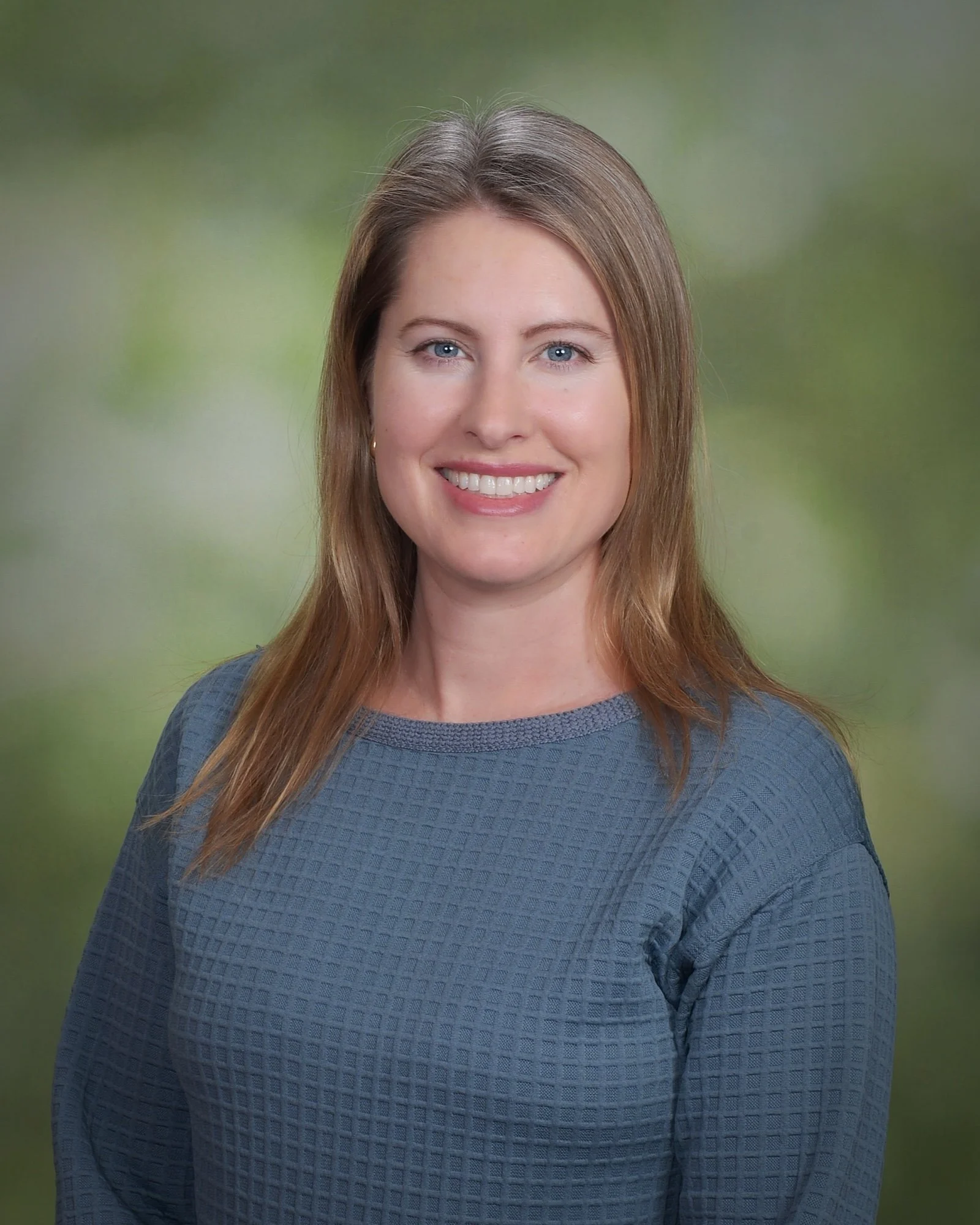 Portrait of a woman with blonde hair, wearing a pearl necklace and a gray blazer.
