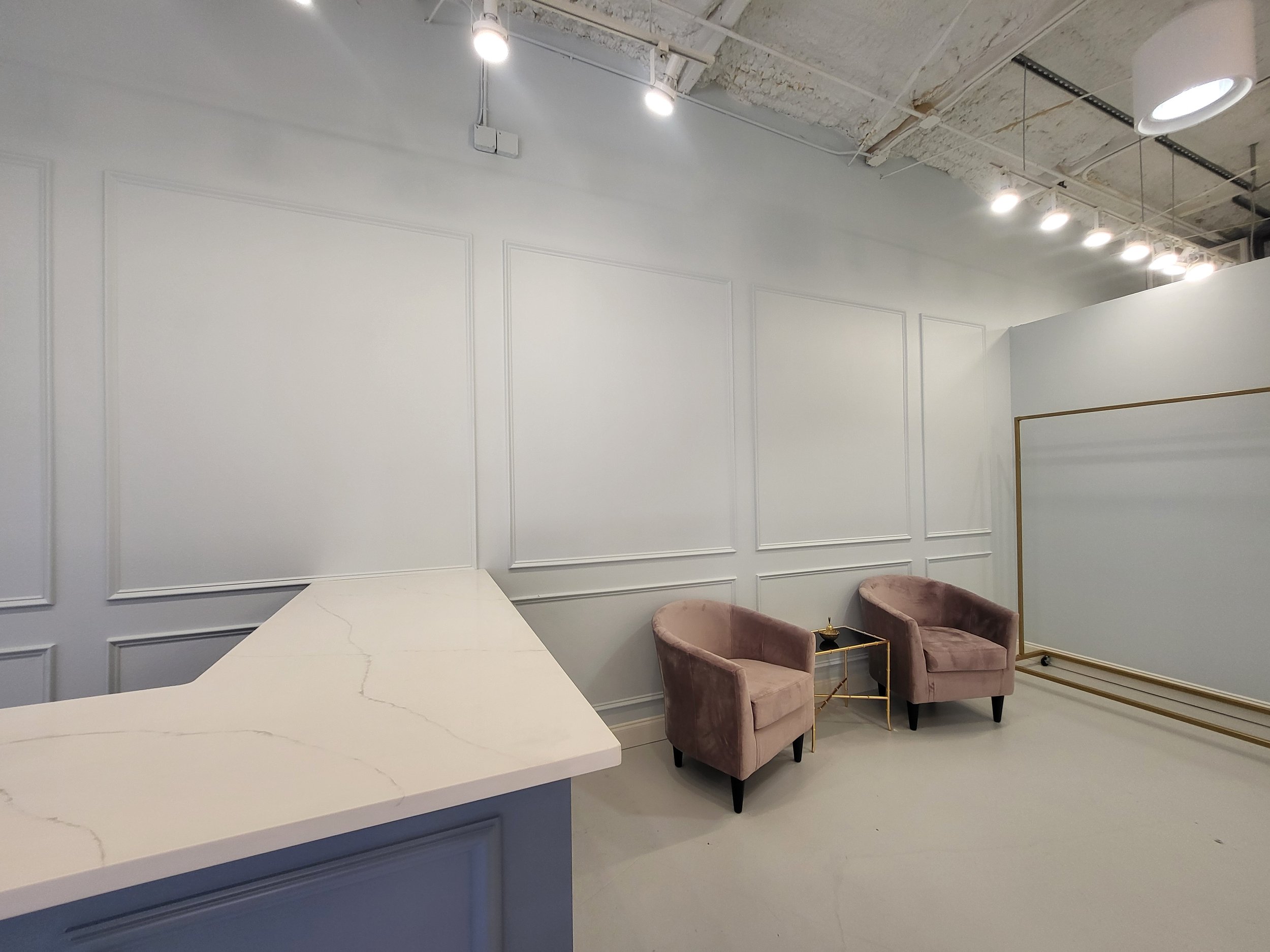 Minimalist interior with marble counter and two upholstered chairs in a light gray room.