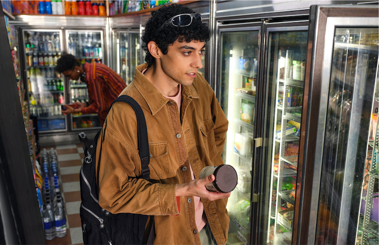 Young male adult picking out icecream in bodega