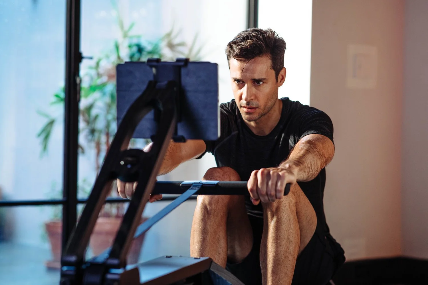 Male on rower looking at Ipad screen