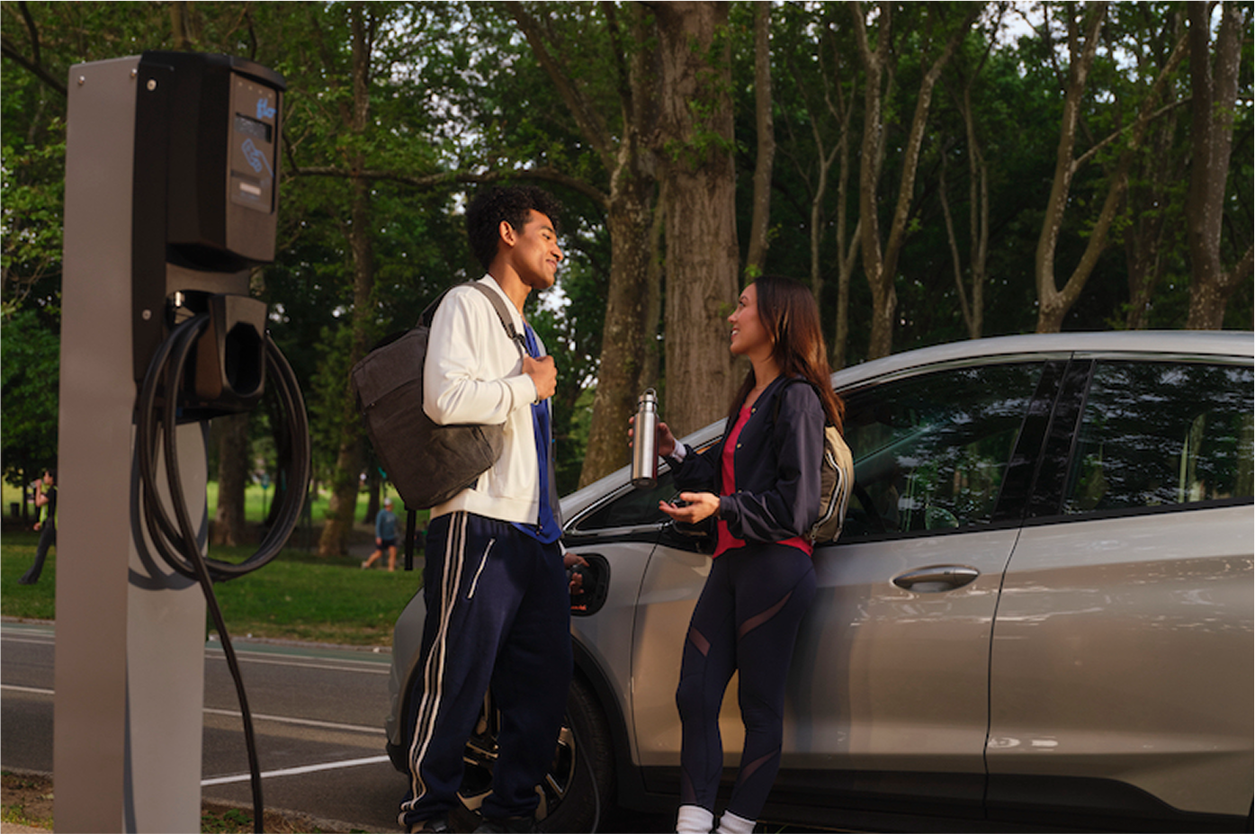 Young couple leaning against electric vehicle 