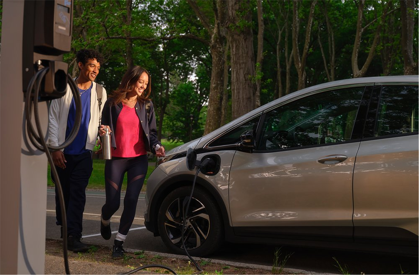 Young couple walking to electric plugged in vehicle