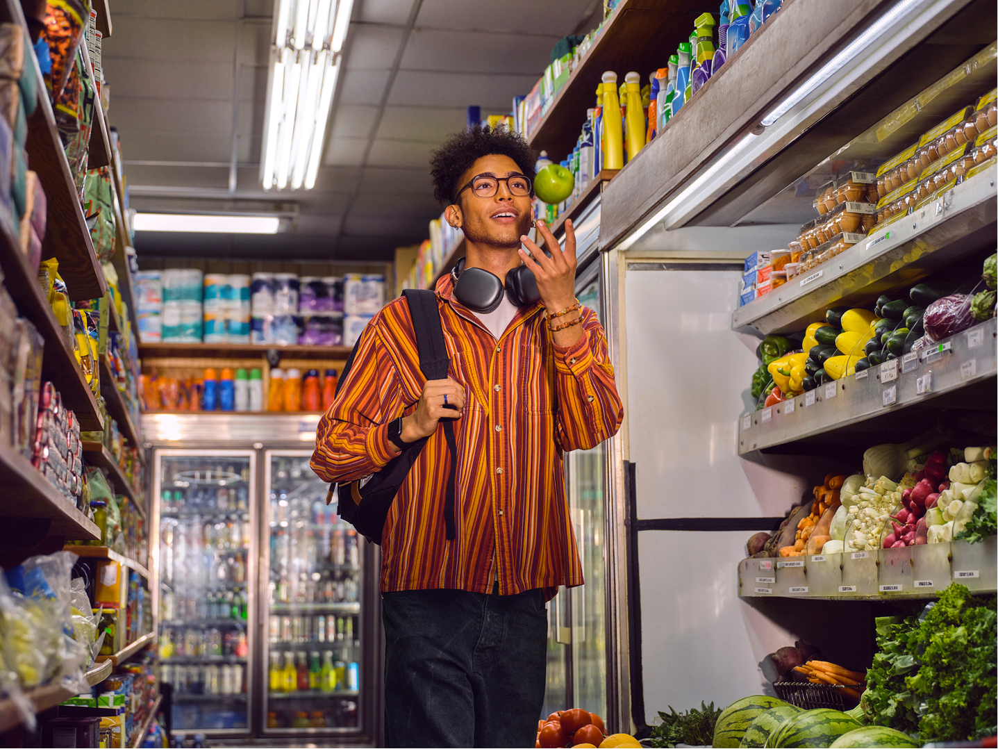 Young male adult in bodega throwing an apple in the air